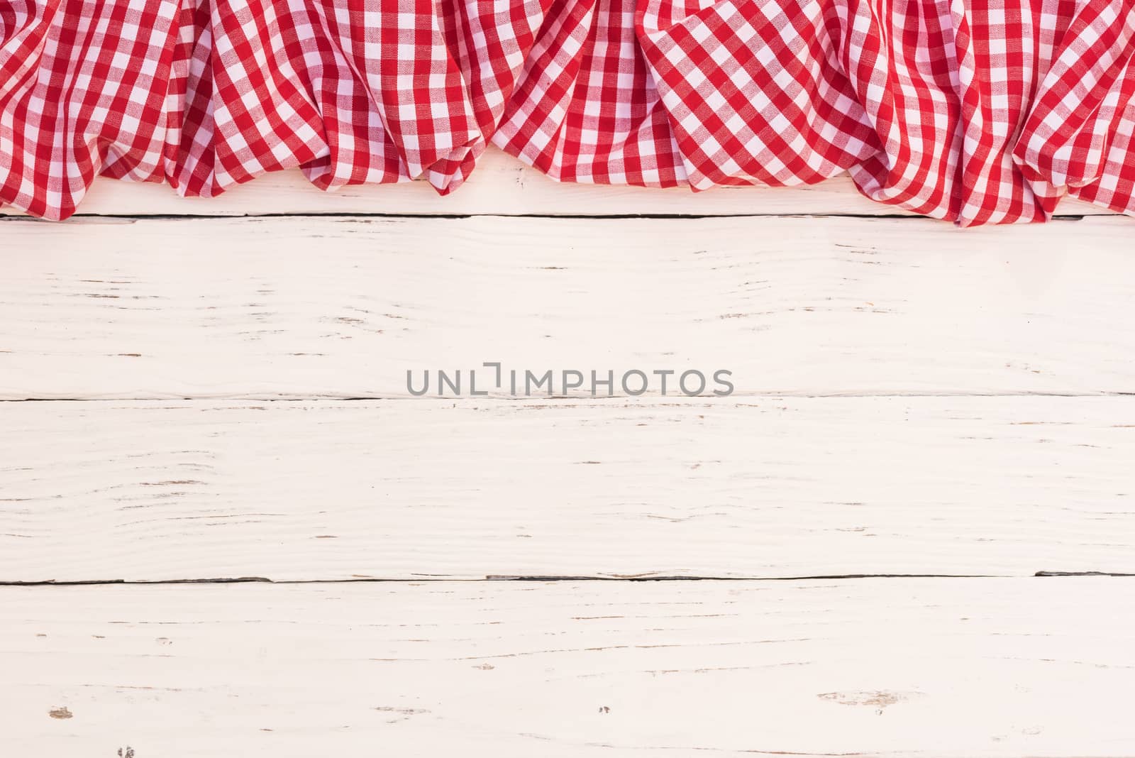 Rustic white wooden table surface with red checkered cloth, top view