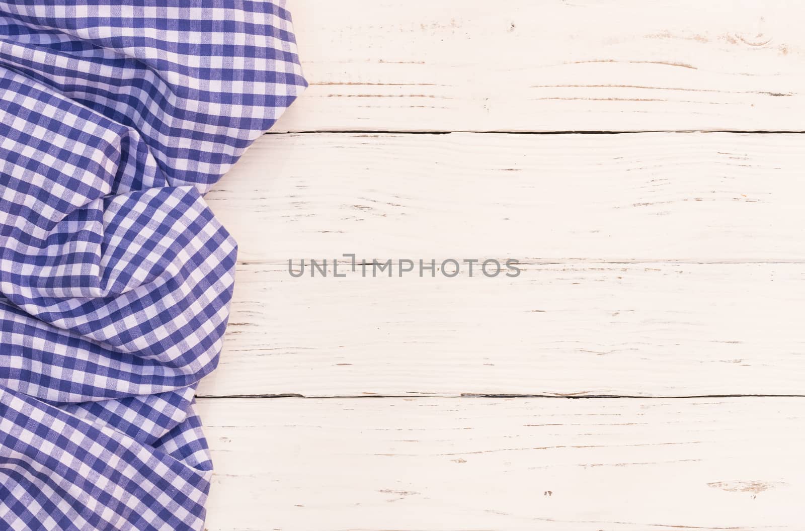 Rustic white wooden table surface with blue checkered cloth, top view
