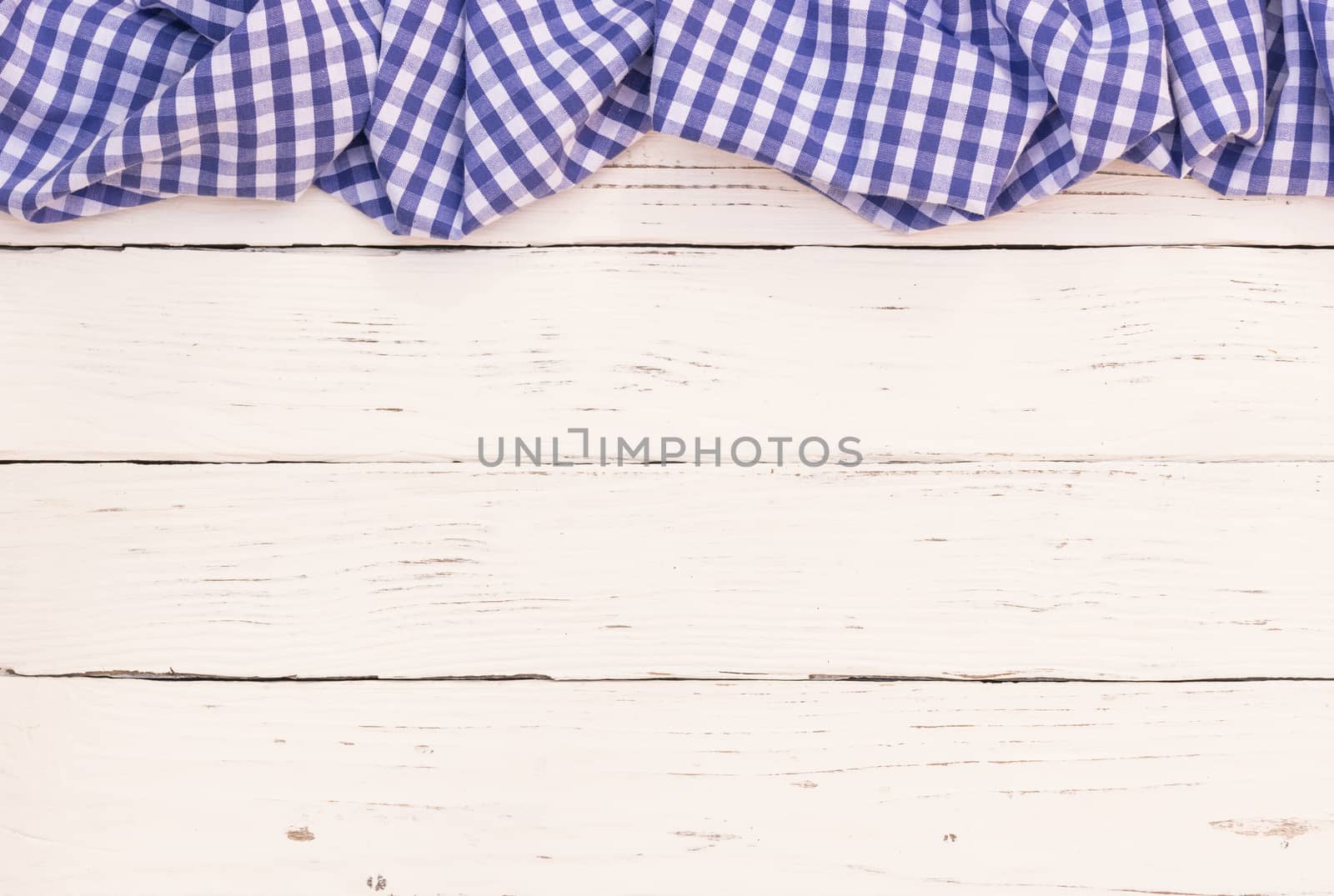 Rustic white wooden table surface with blue checkered cloth, top view