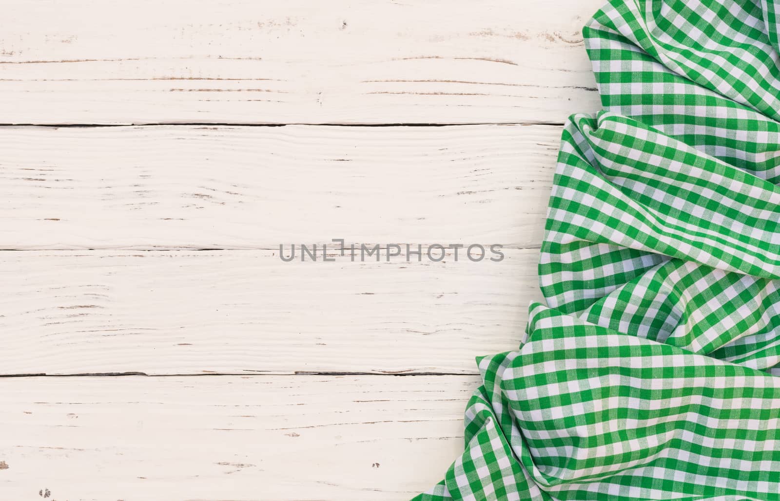 Rustic white wooden table surface with green checkered cloth, top view