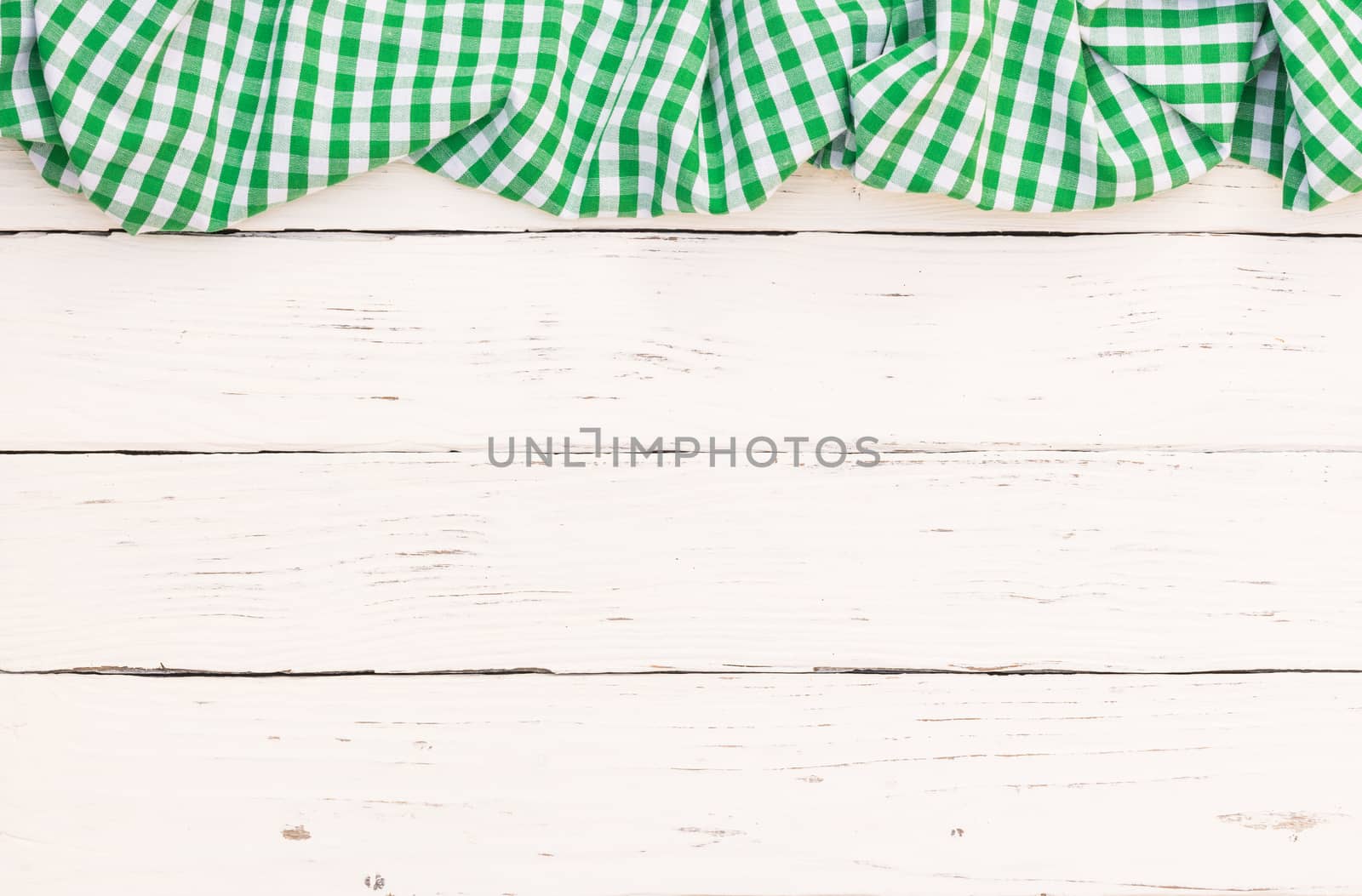 Rustic white wooden table surface with green checkered cloth, top view