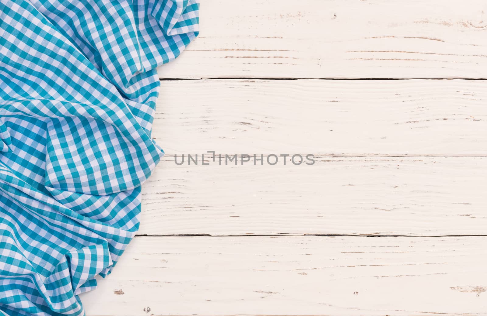 Rustic white wooden table surface with blue checkered cloth, top view