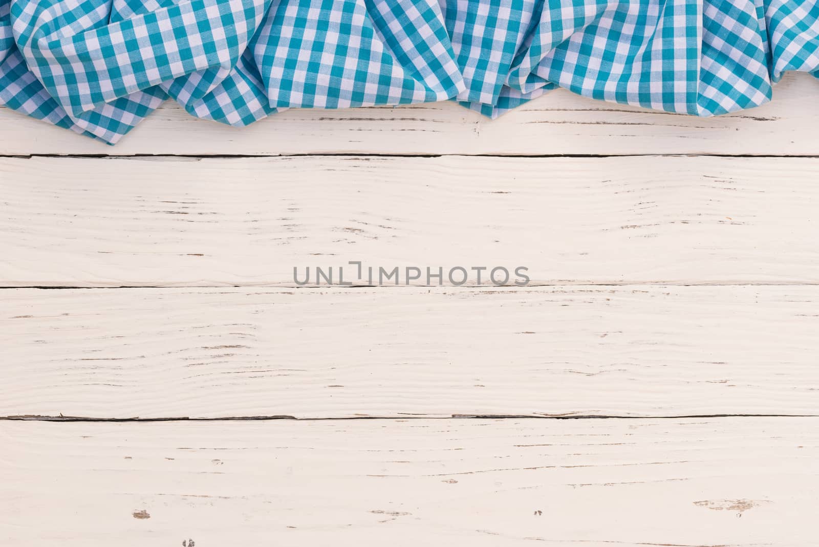 Rustic white wooden table surface with blue checkered cloth, top view