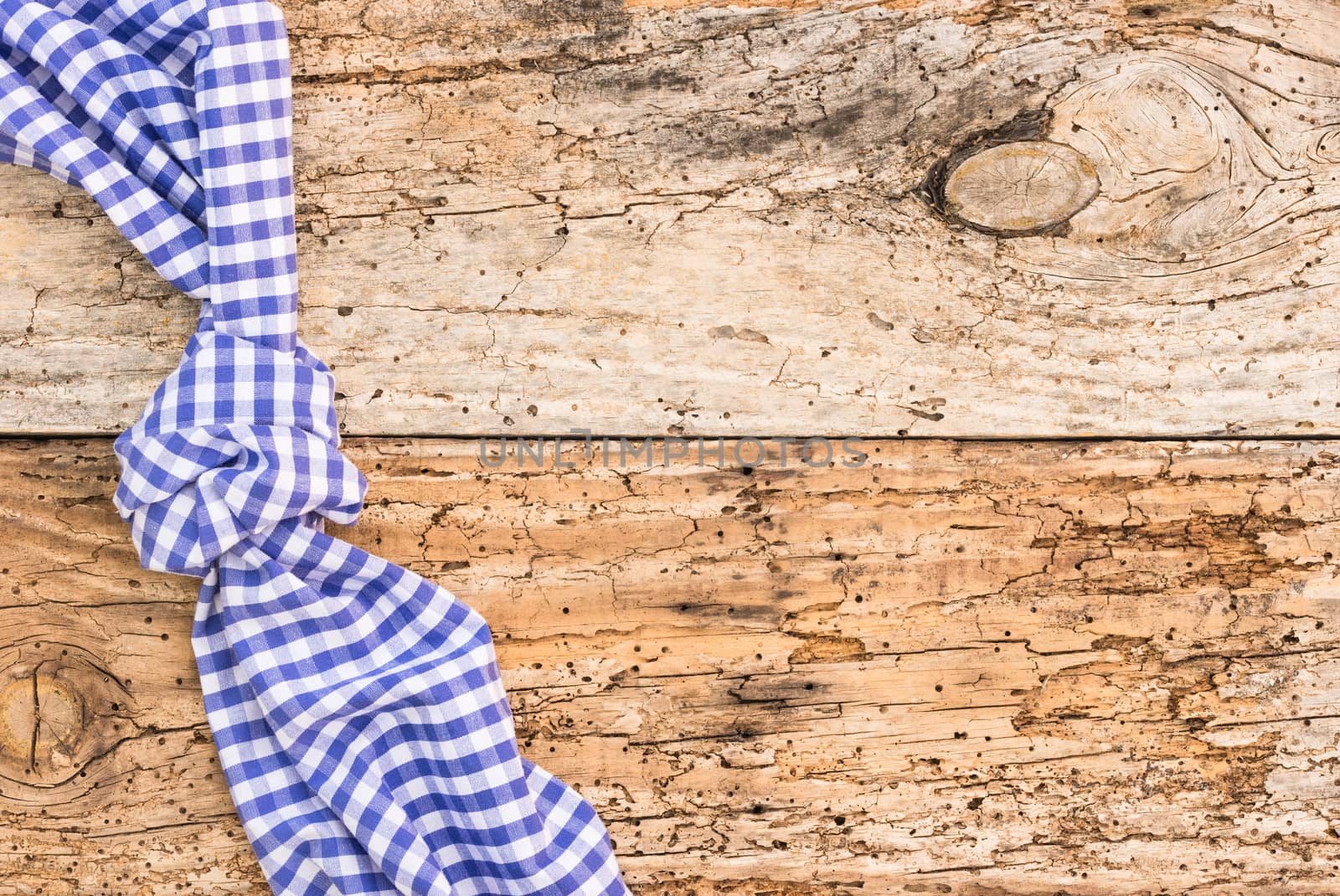 Rustic wooden table surface with blue checkered cloth, top view