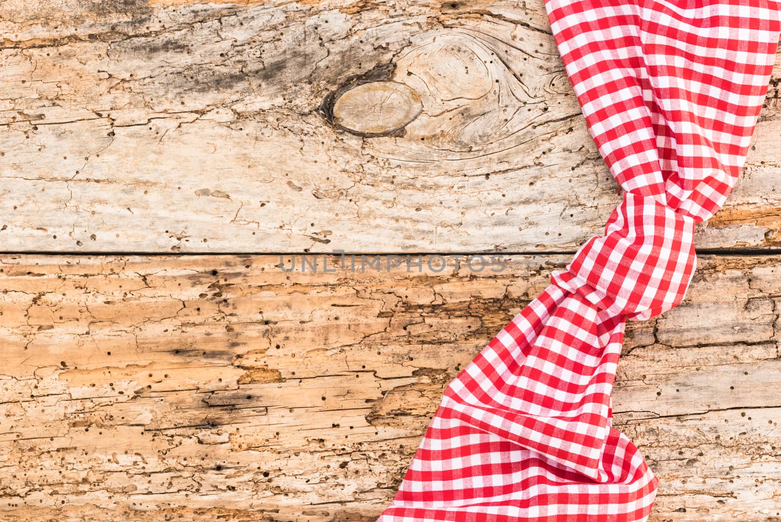 Rustic old wooden table surface with red checkered cloth, top view