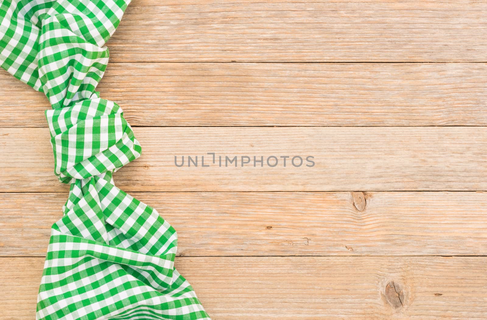 Green checked tablecloth on wooden table, top view with copy space