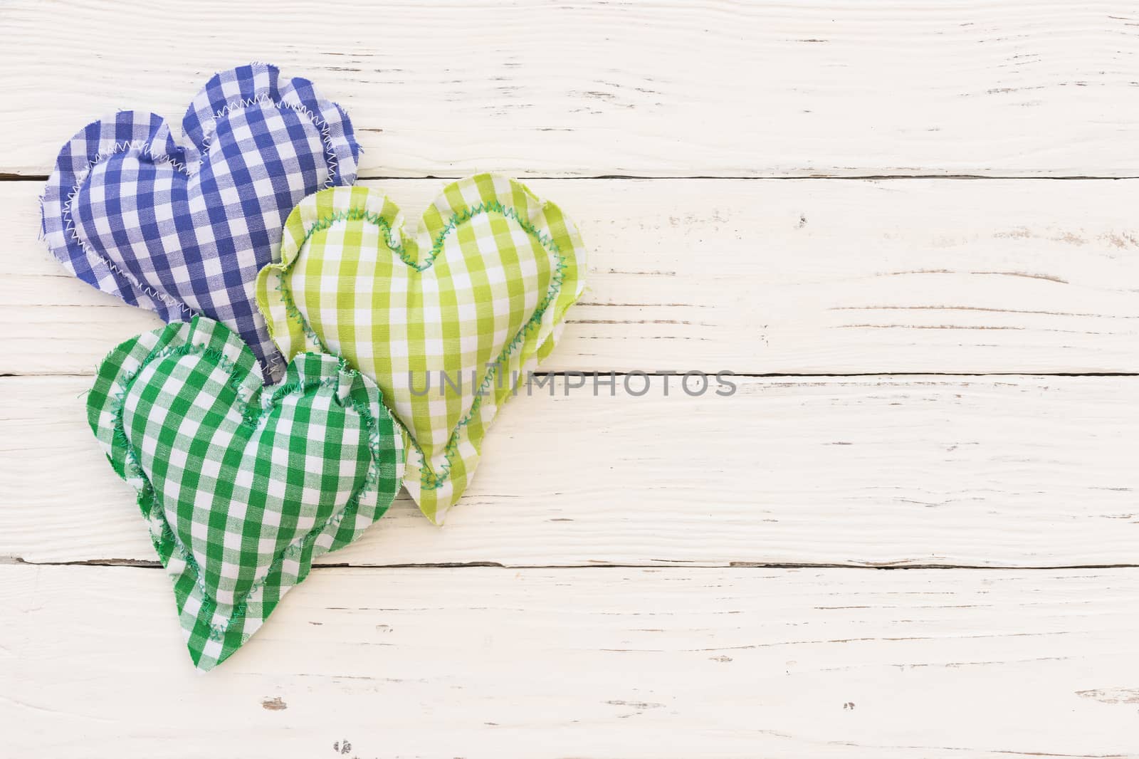 Blue and green hearts on white wooden background with copy space