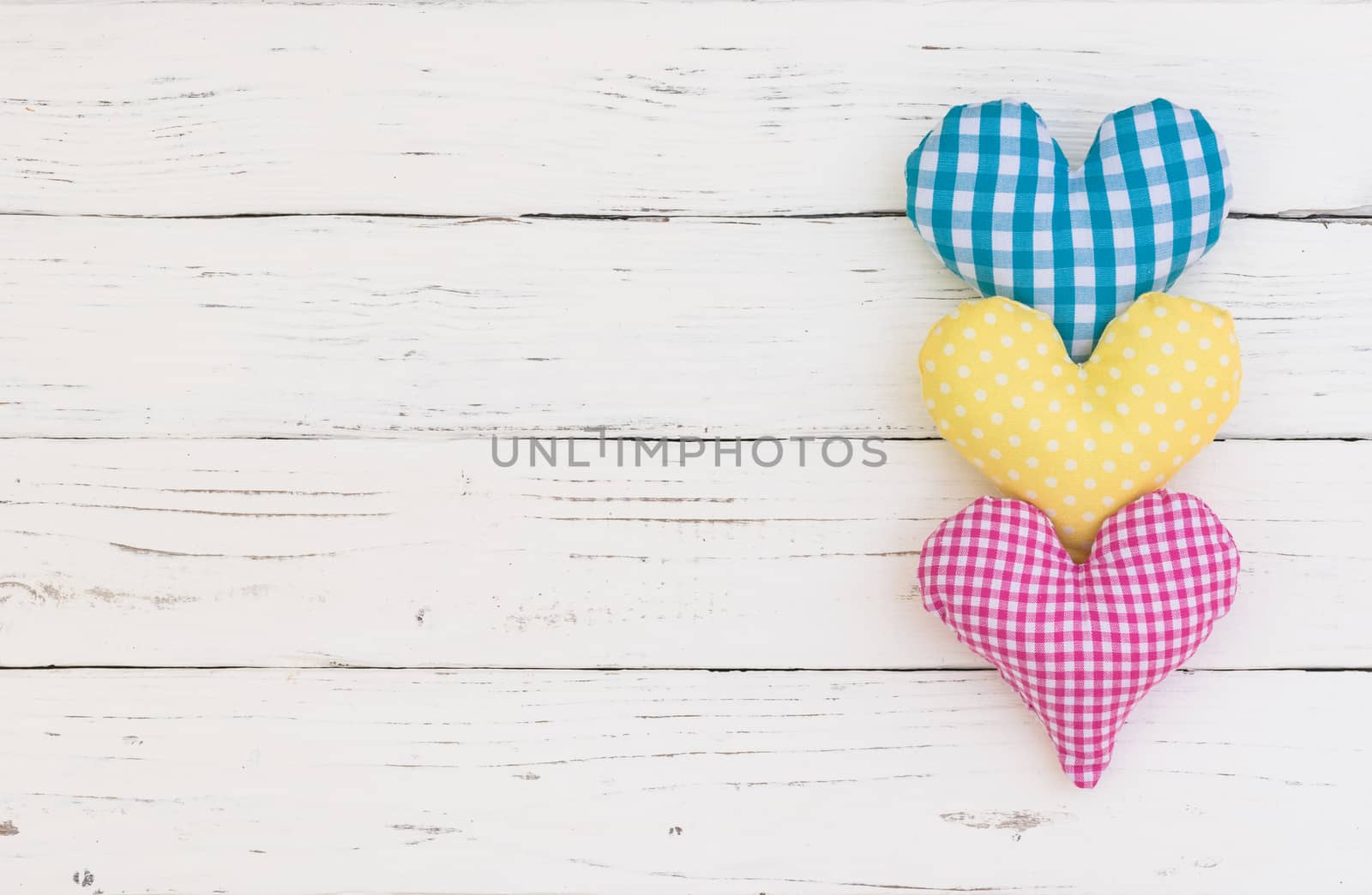 Blue, yellow and pink heart on white wood background with copy space