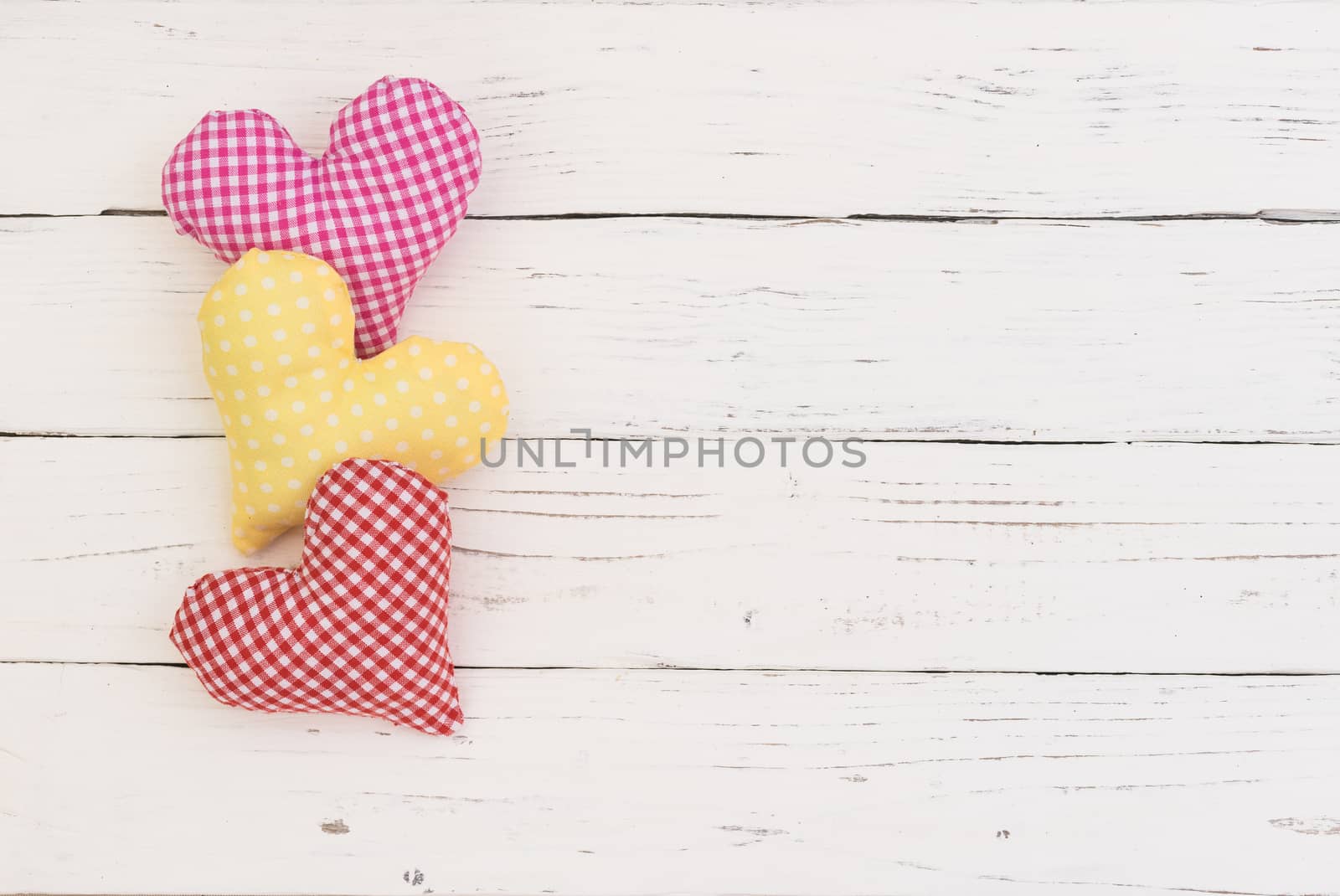 Pink, yellow and red heart border on white wooden background with copy space