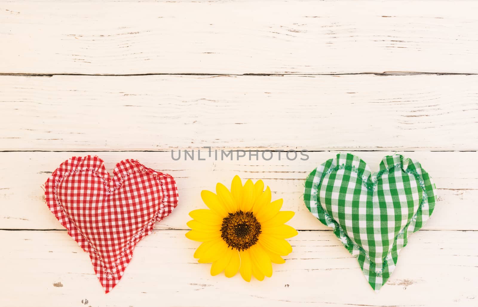 Red and green heart with yellow flower on white wooden background with copy space