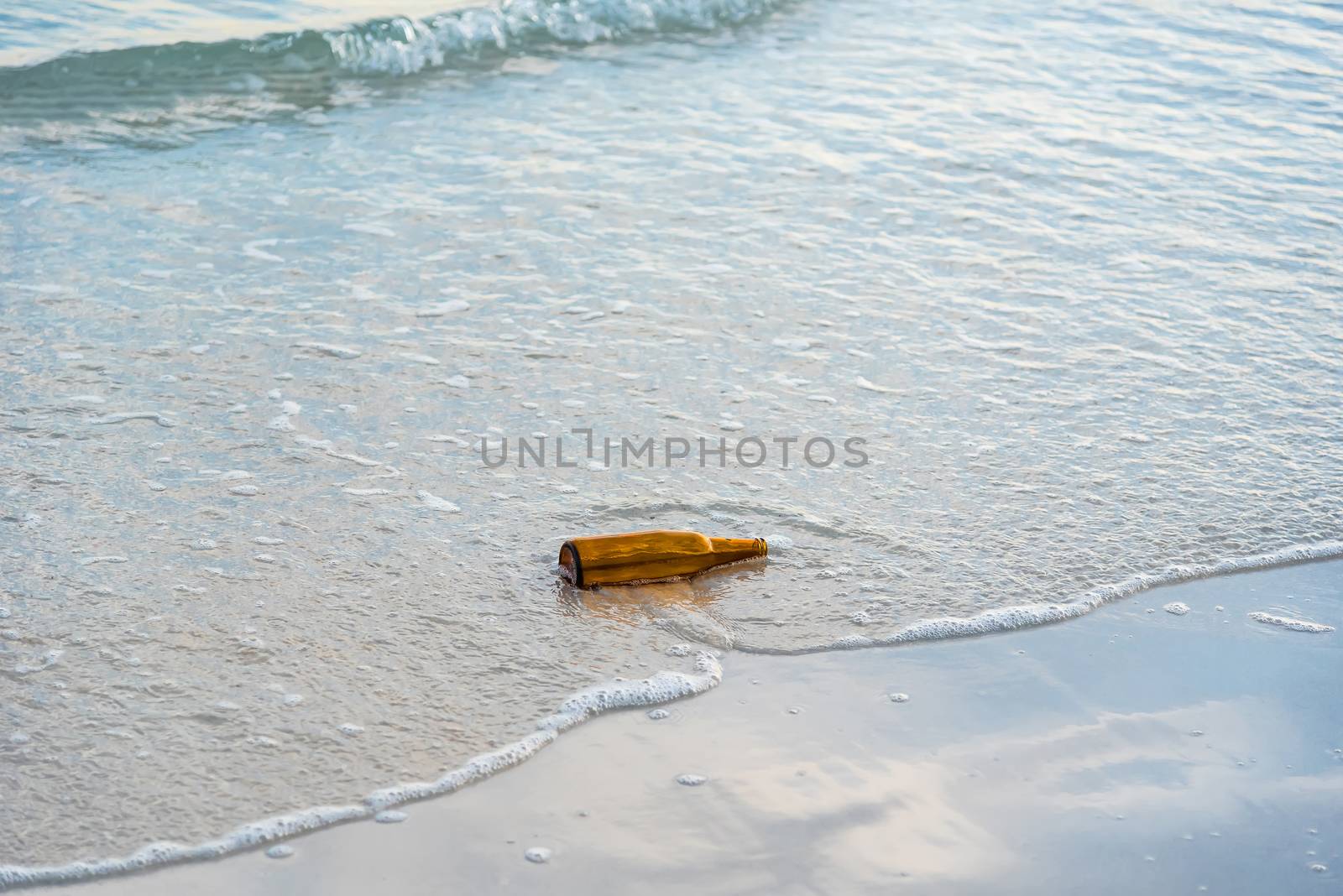 Brown glass bottle on Tawaen Beach in the dawn, the sun was rising, morning sunrise time on Koh Lan island.