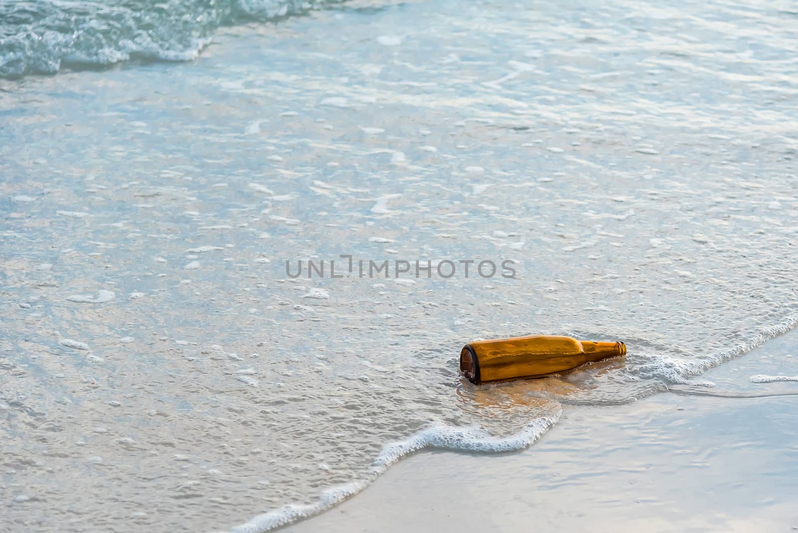 Brown glass bottle on Tawaen Beach in the dawn, the sun was risi by Bubbers