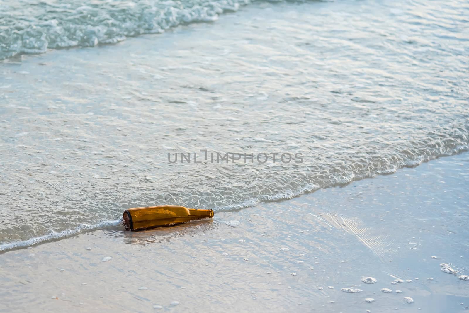 Brown glass bottle on Tawaen Beach in the dawn, the sun was rising, morning sunrise time on Koh Lan island.