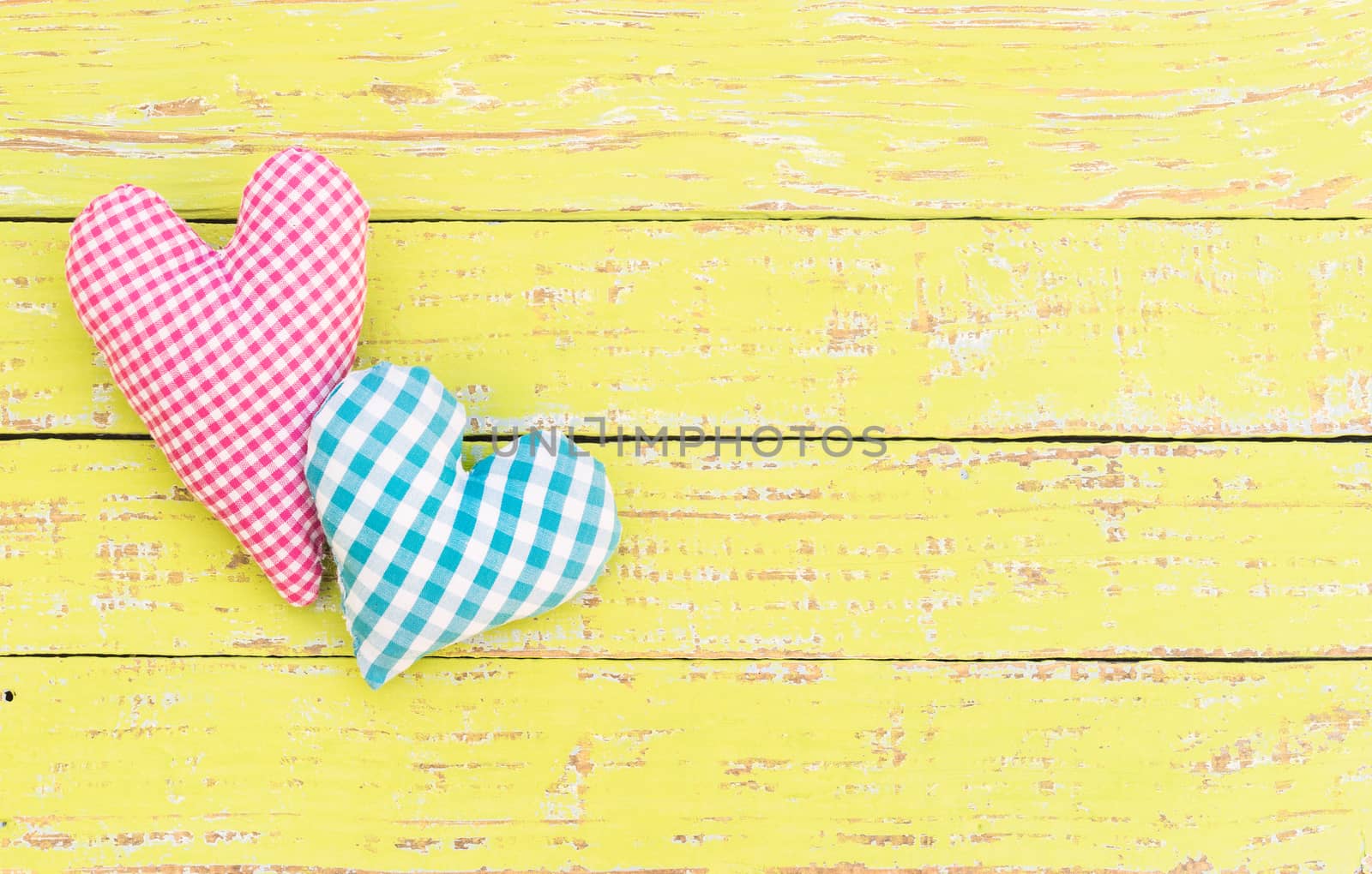 Pink and blue heart on yellow wood with copy space