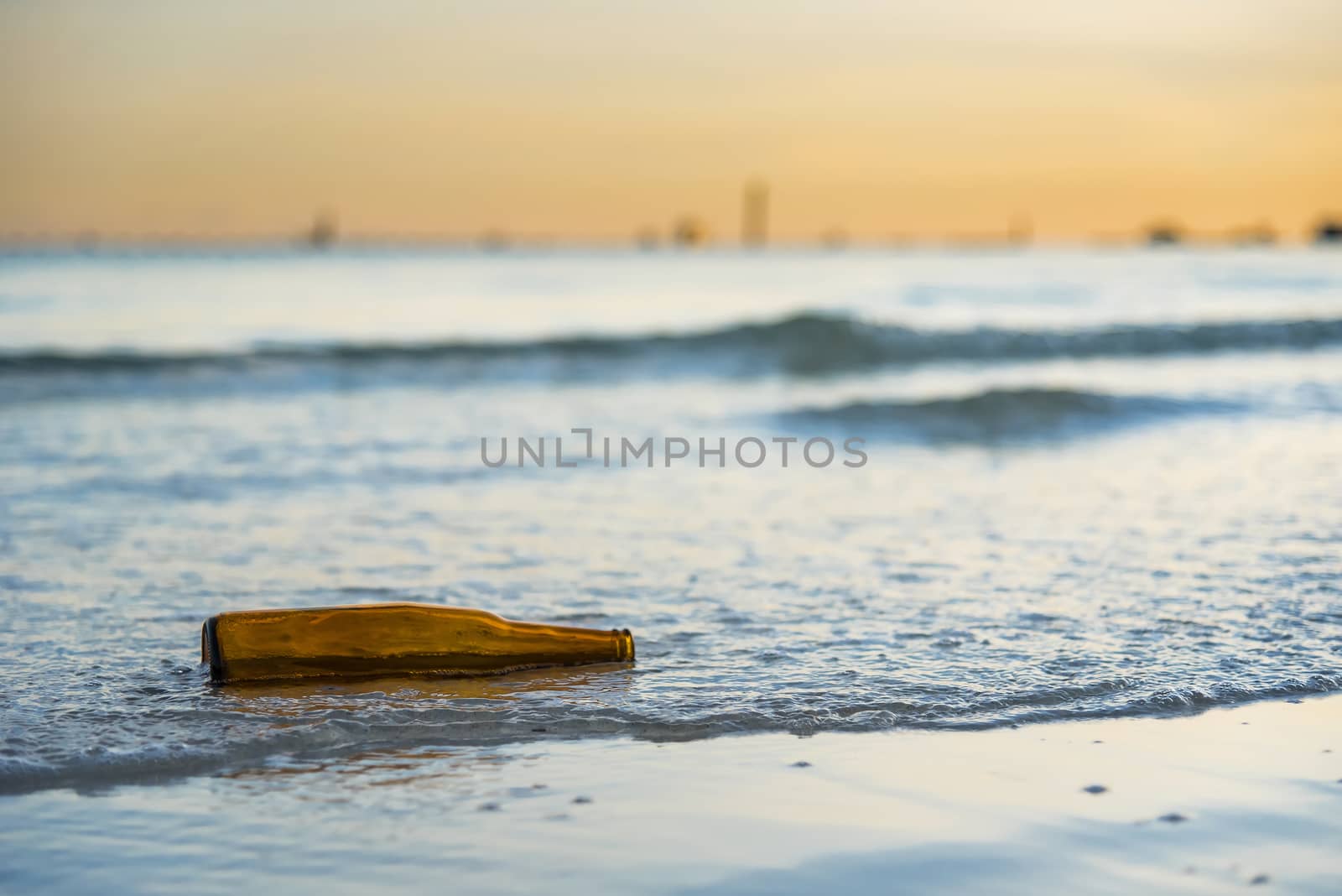 Brown glass bottle on Tawaen Beach in the dawn, the sun was risi by Bubbers