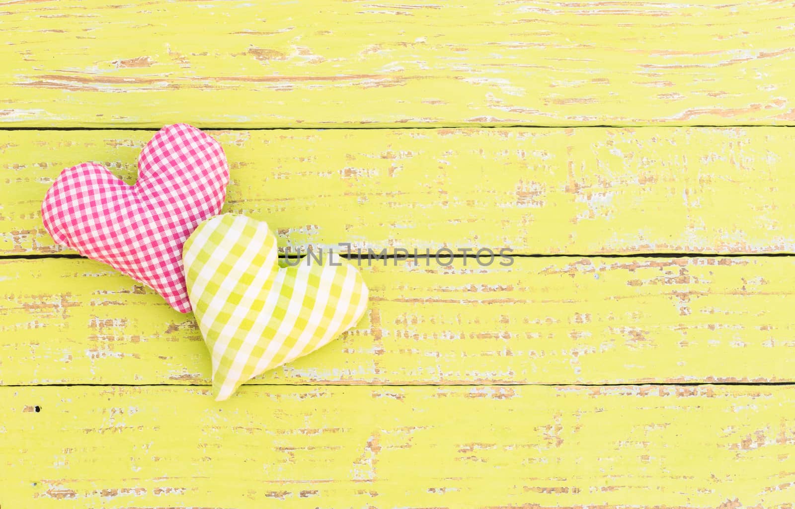 Two hearts on yellow wooden background with copy space