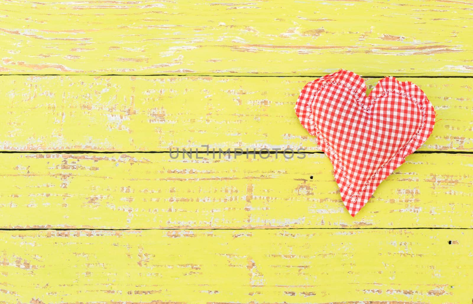 Romantic red heart on yellow wood background for Valentine card with copy space