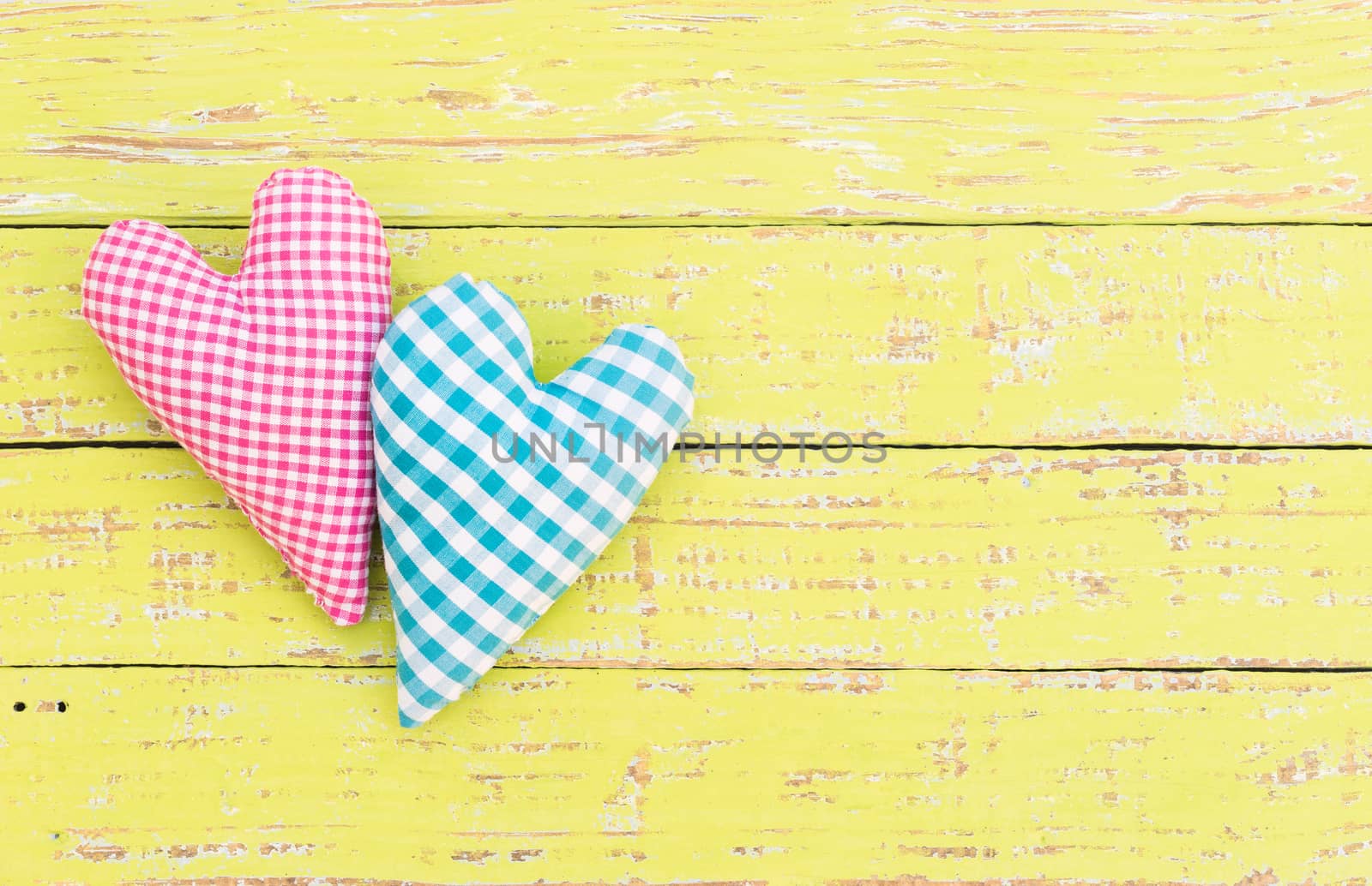 Pink and blue heart on yellow wooden background with copy space