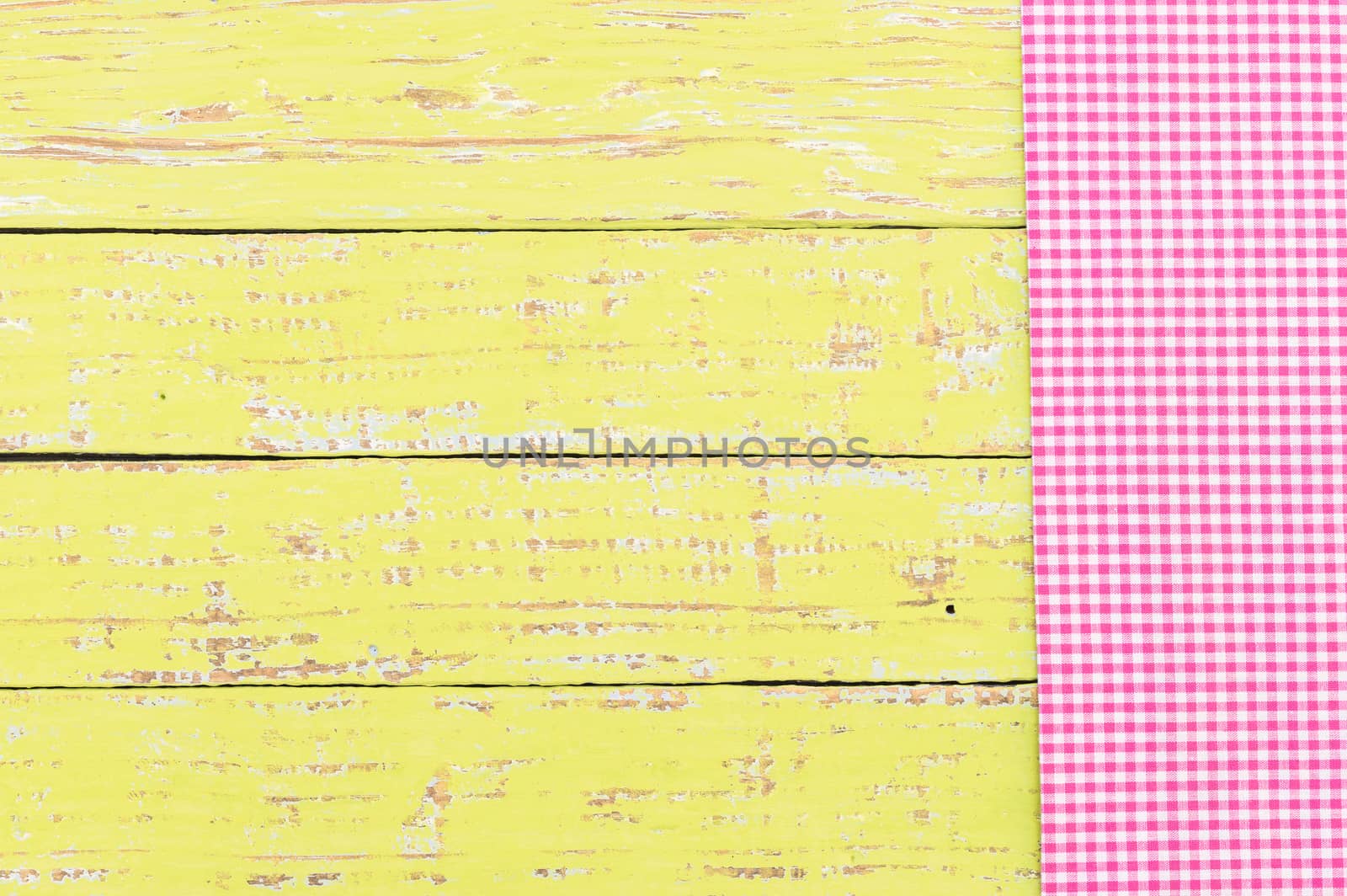 Yellow wooden table background rustic texture, with pink checkered tablecloth, high angel view