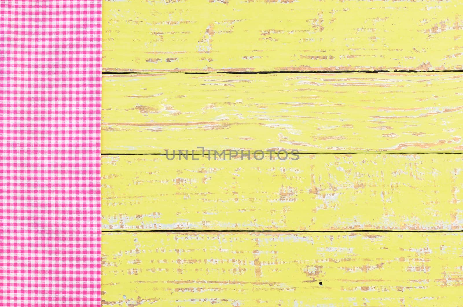 Pink checked tablecloth on rustic colored wooden table background, top view