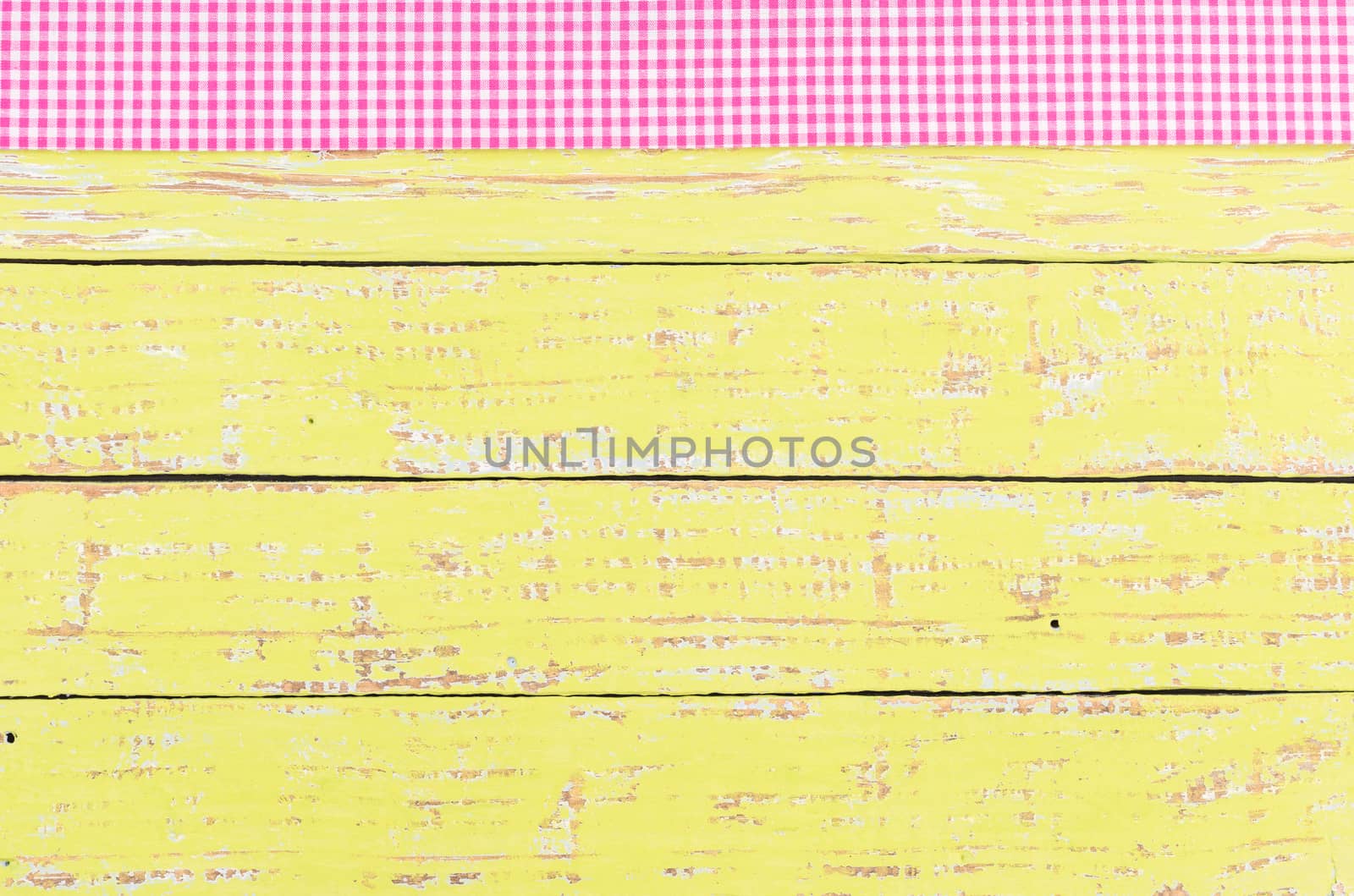 Rustic wooden table surface with pink checkered cloth, top view