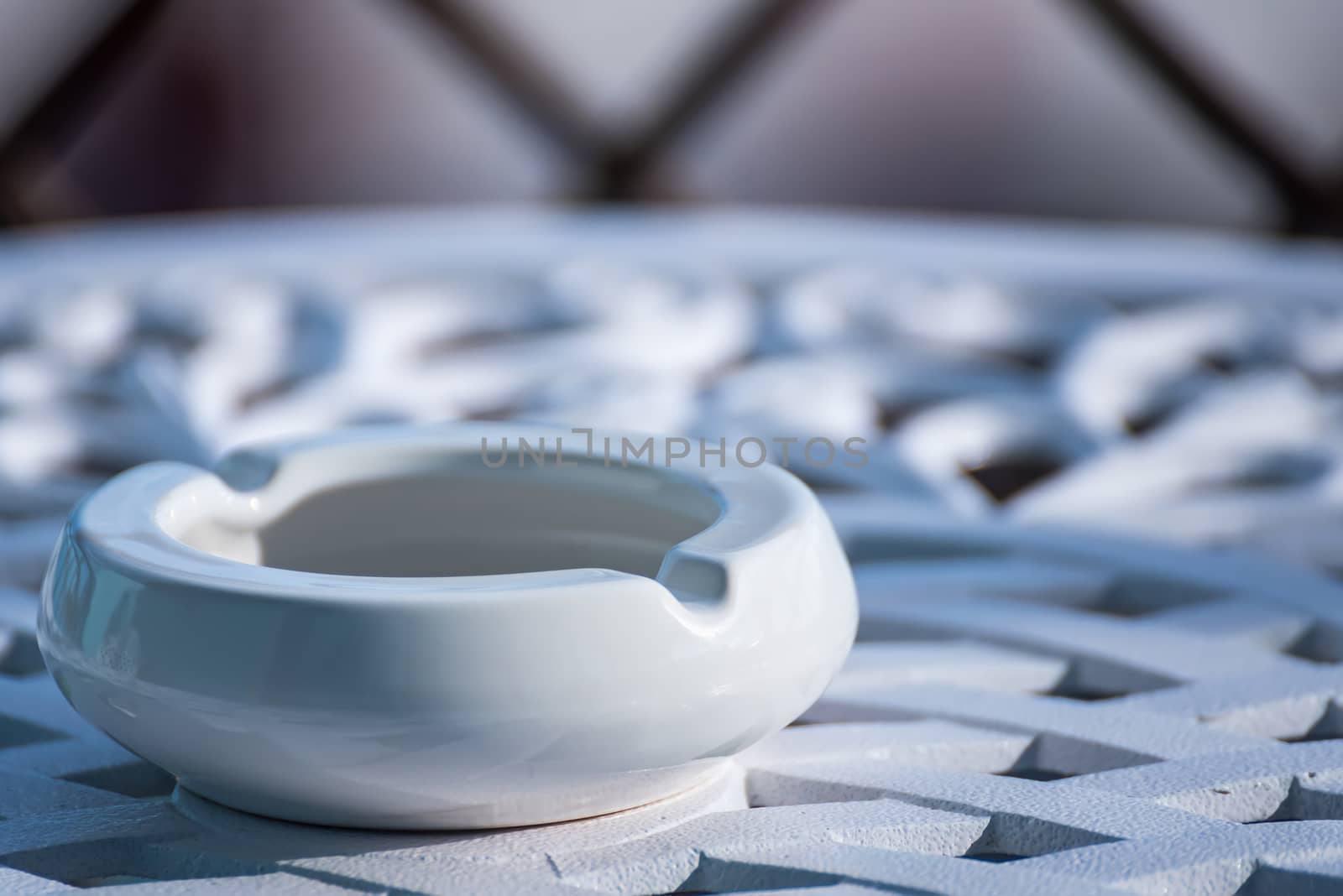White ceramic ashtray on the metal table by Bubbers