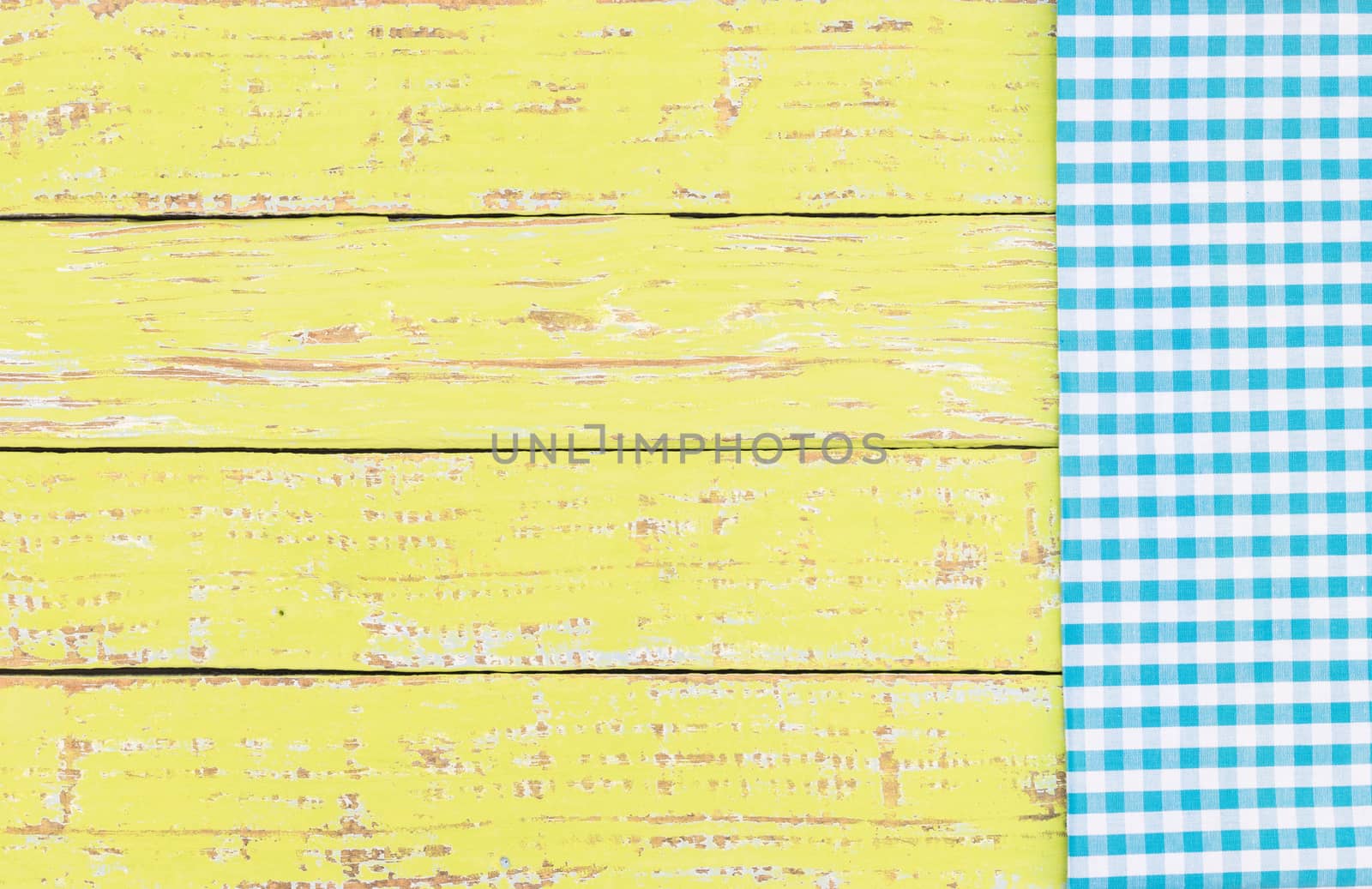 Yellow wooden table background rustic texture, with blue checkered tablecloth, high angel view