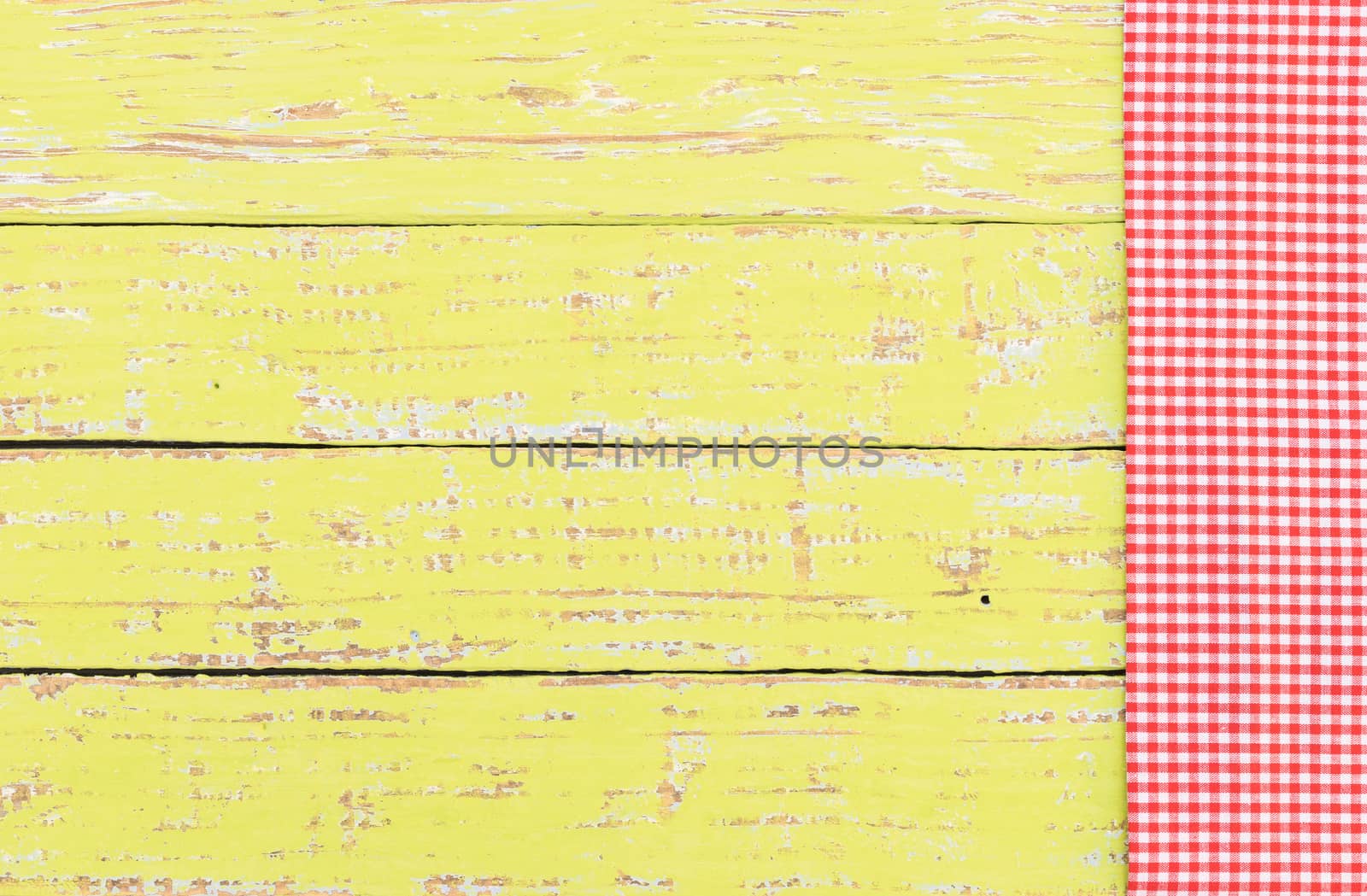 Yellow wooden table background rustic texture, with red checkered tablecloth, high angel view