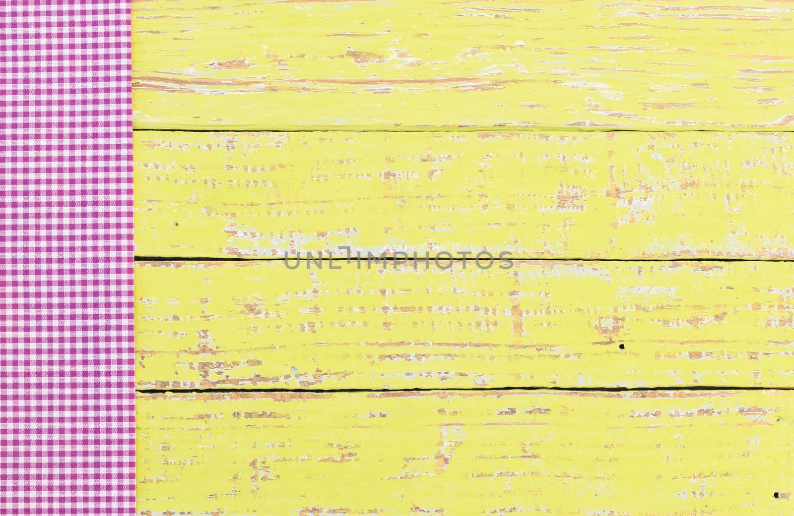 Yellow wooden table background rustic texture, with purple checkered tablecloth, high angel view