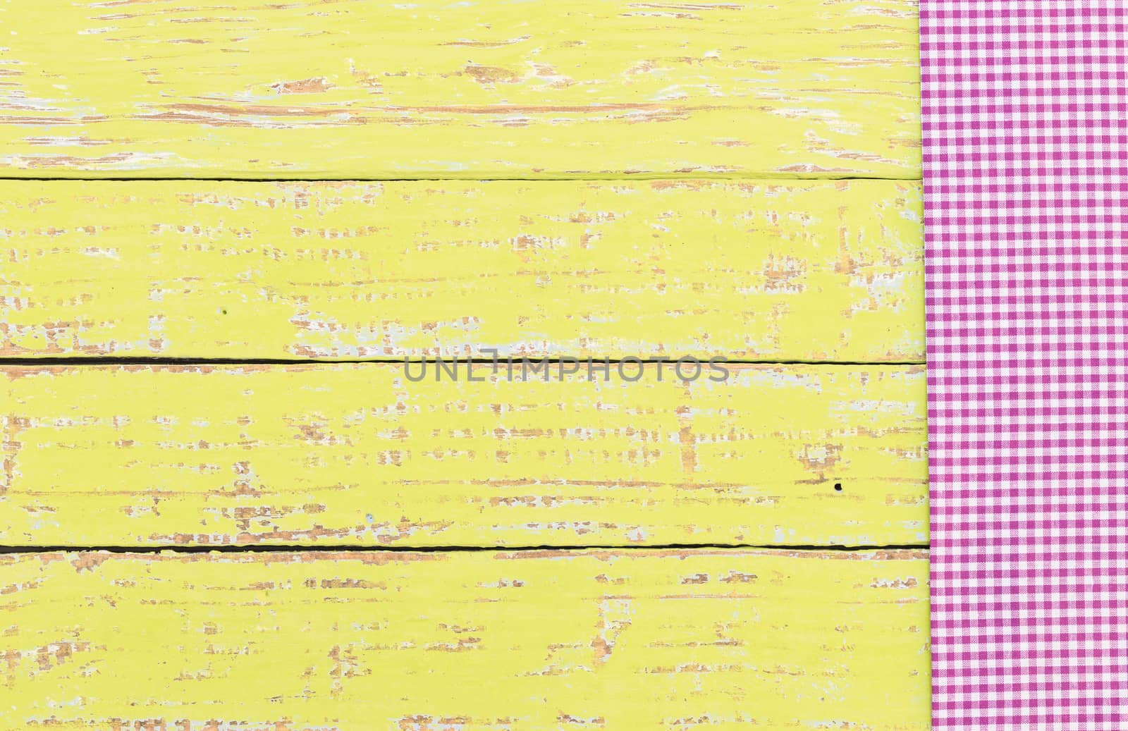 Purple checked tablecloth on rustic wooden table background, top view