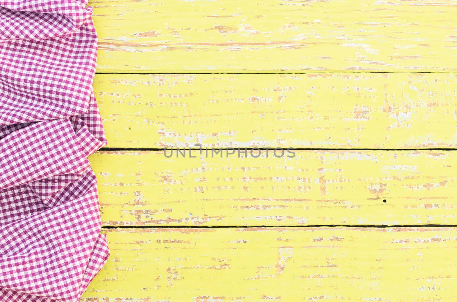 Yellow wooden table background rustic texture, with purple checkered tablecloth, high angel view

