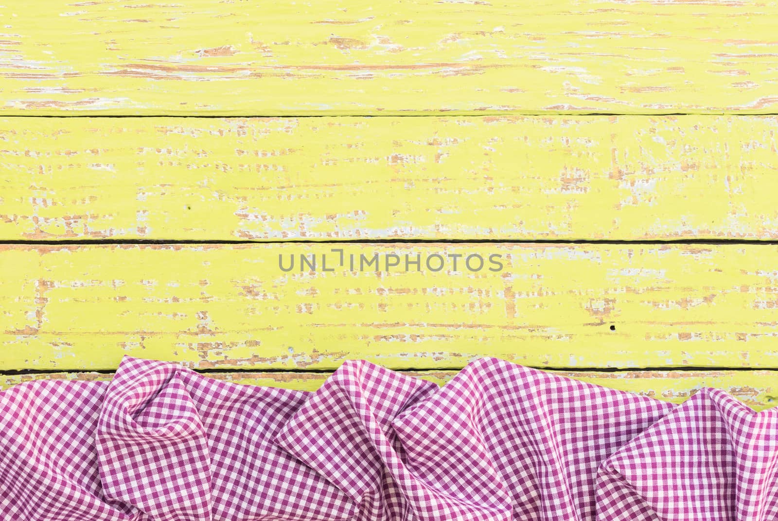 Yellow wooden table background rustic texture, with purple checkered tablecloth, high angel view