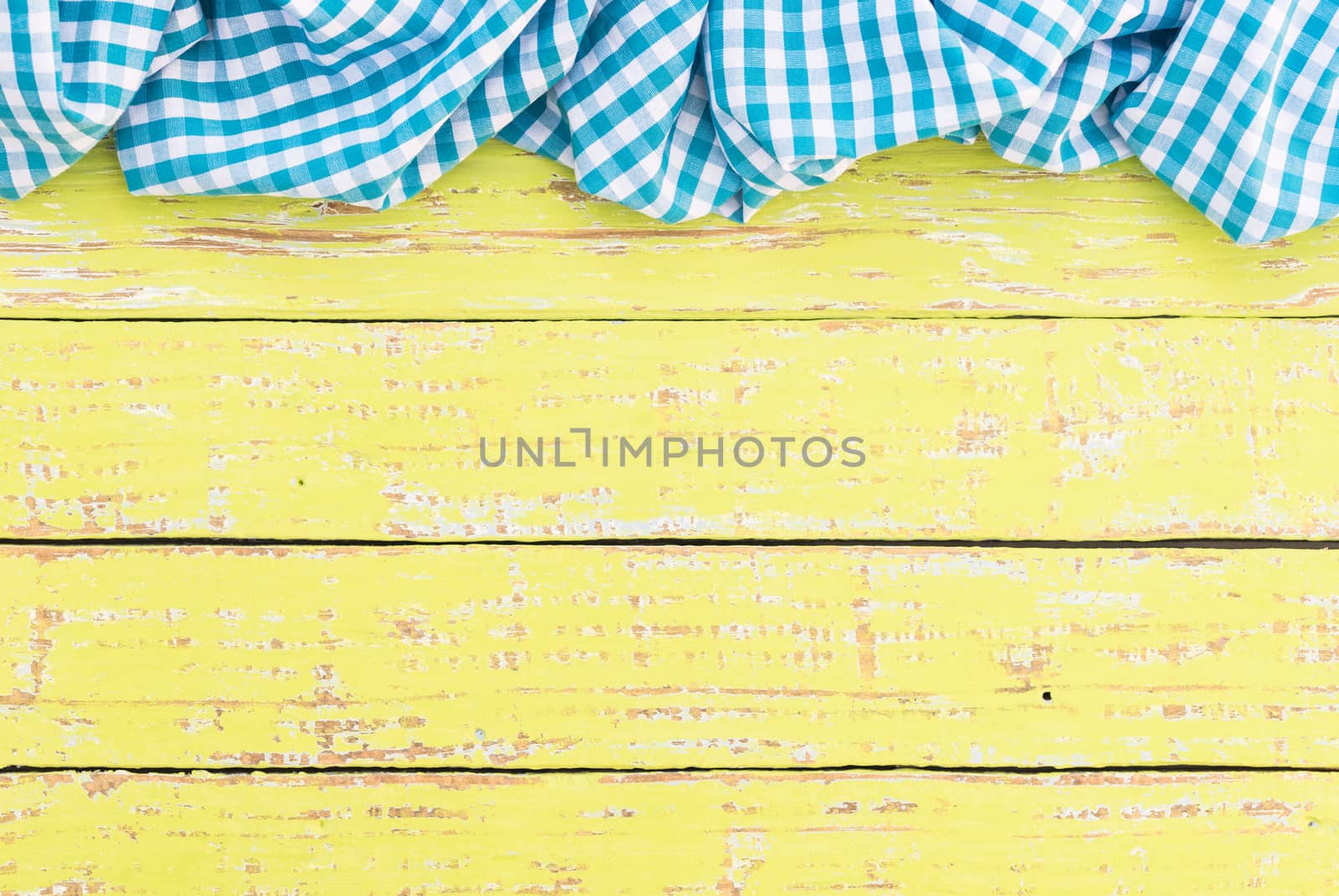 Yellow wooden table background rustic texture, with blue checkered tablecloth, high angel view