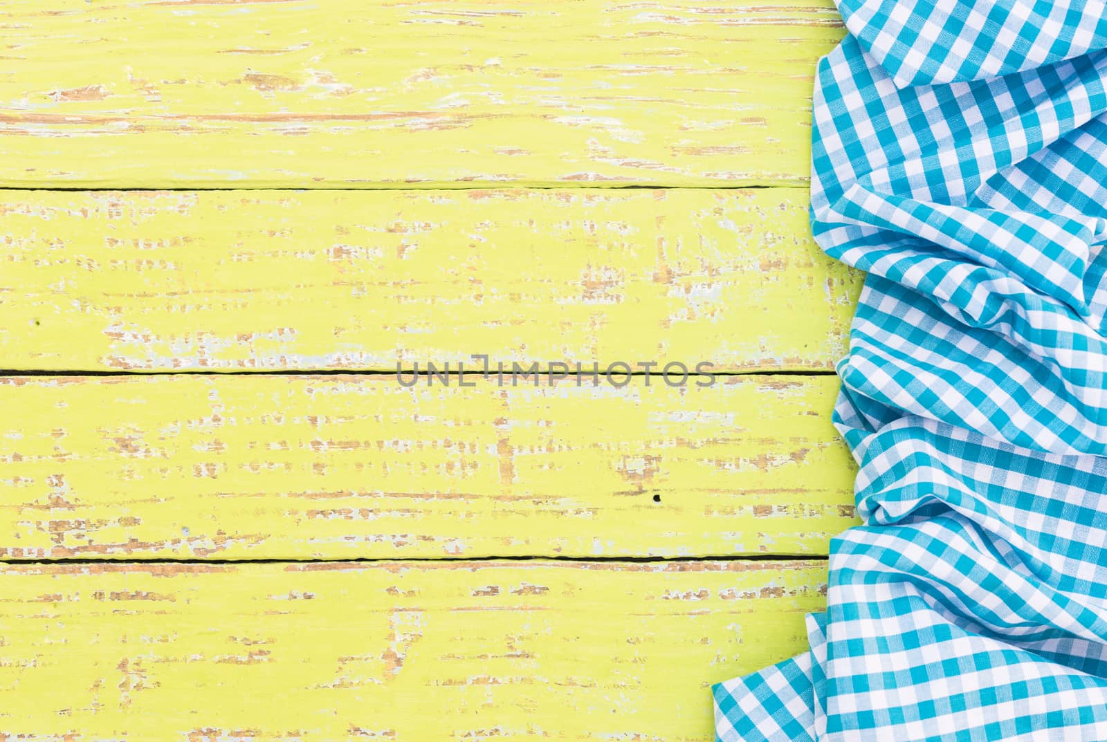 Yellow wooden table background rustic texture, with blue checkered tablecloth, high angel view