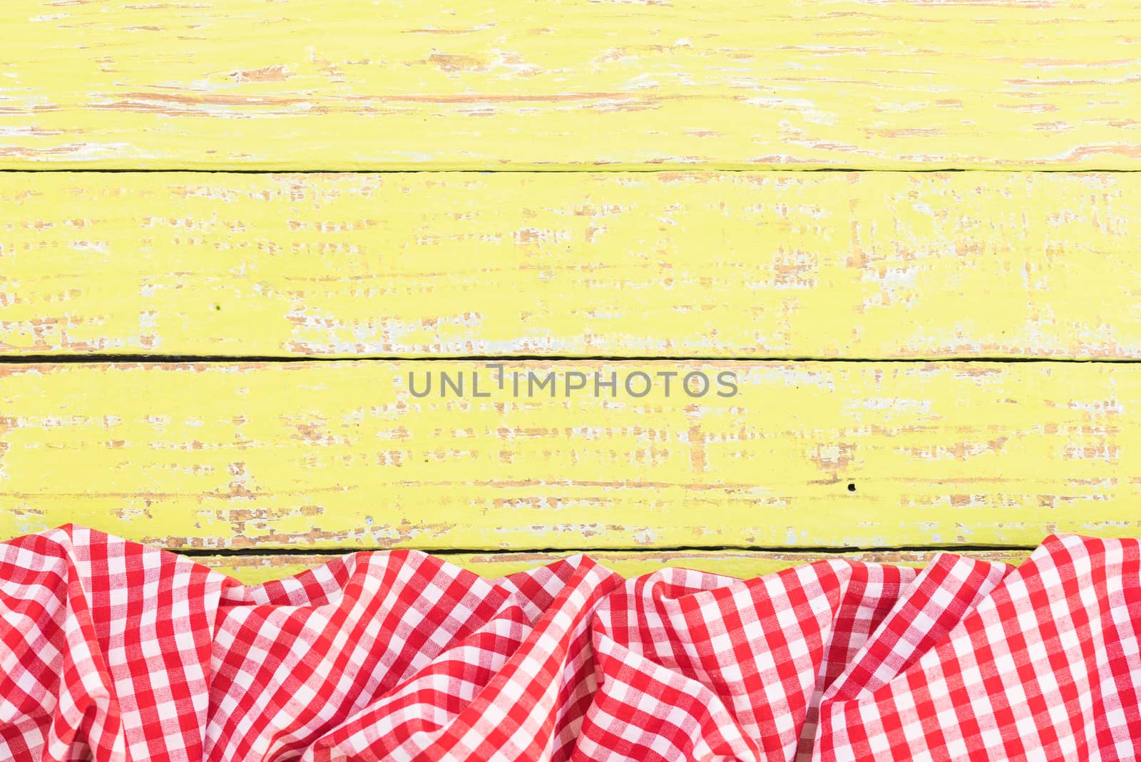 Yellow wooden table background rustic texture, with red checkered tablecloth, high angel view

