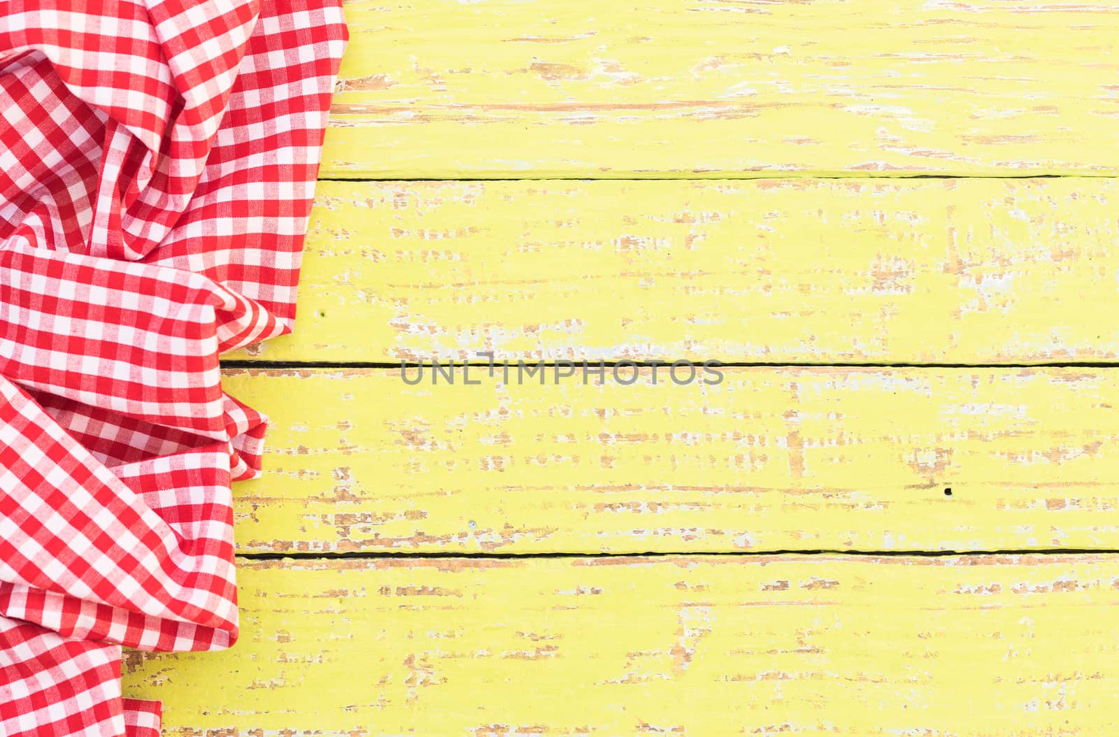 Yellow wooden table background rustic texture, with red checkered tablecloth, high angel view