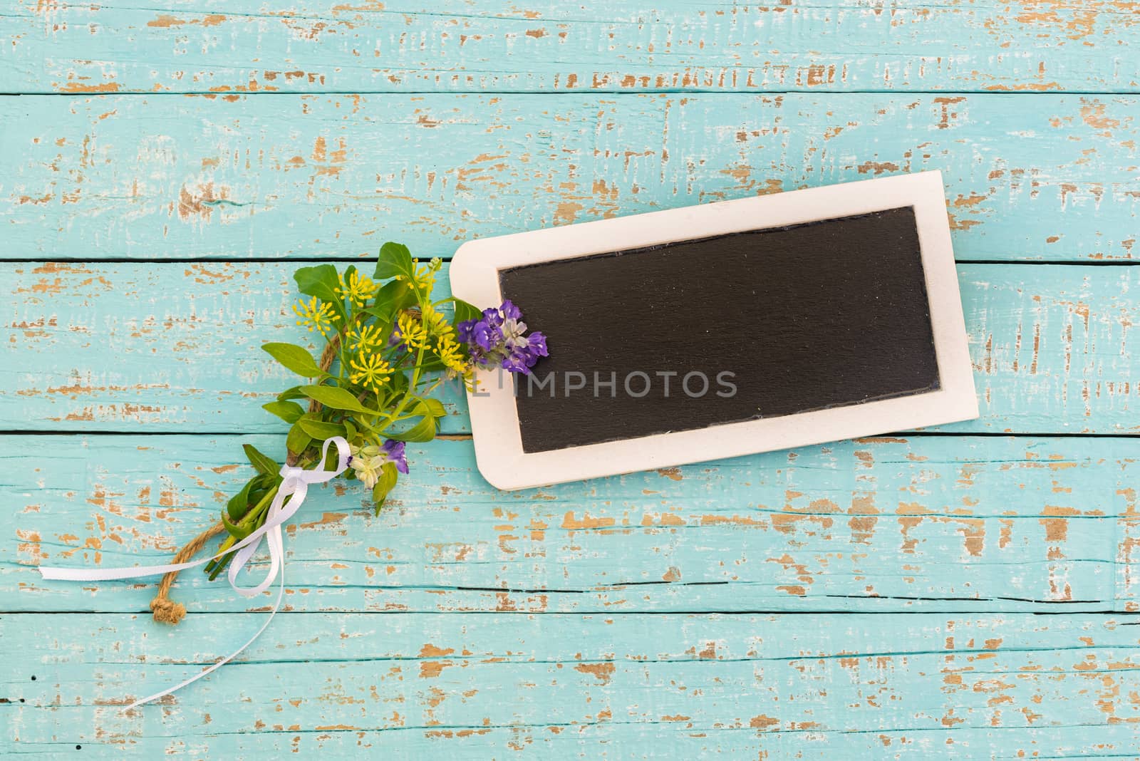 Blank small blackboard with flowers on blue wood background