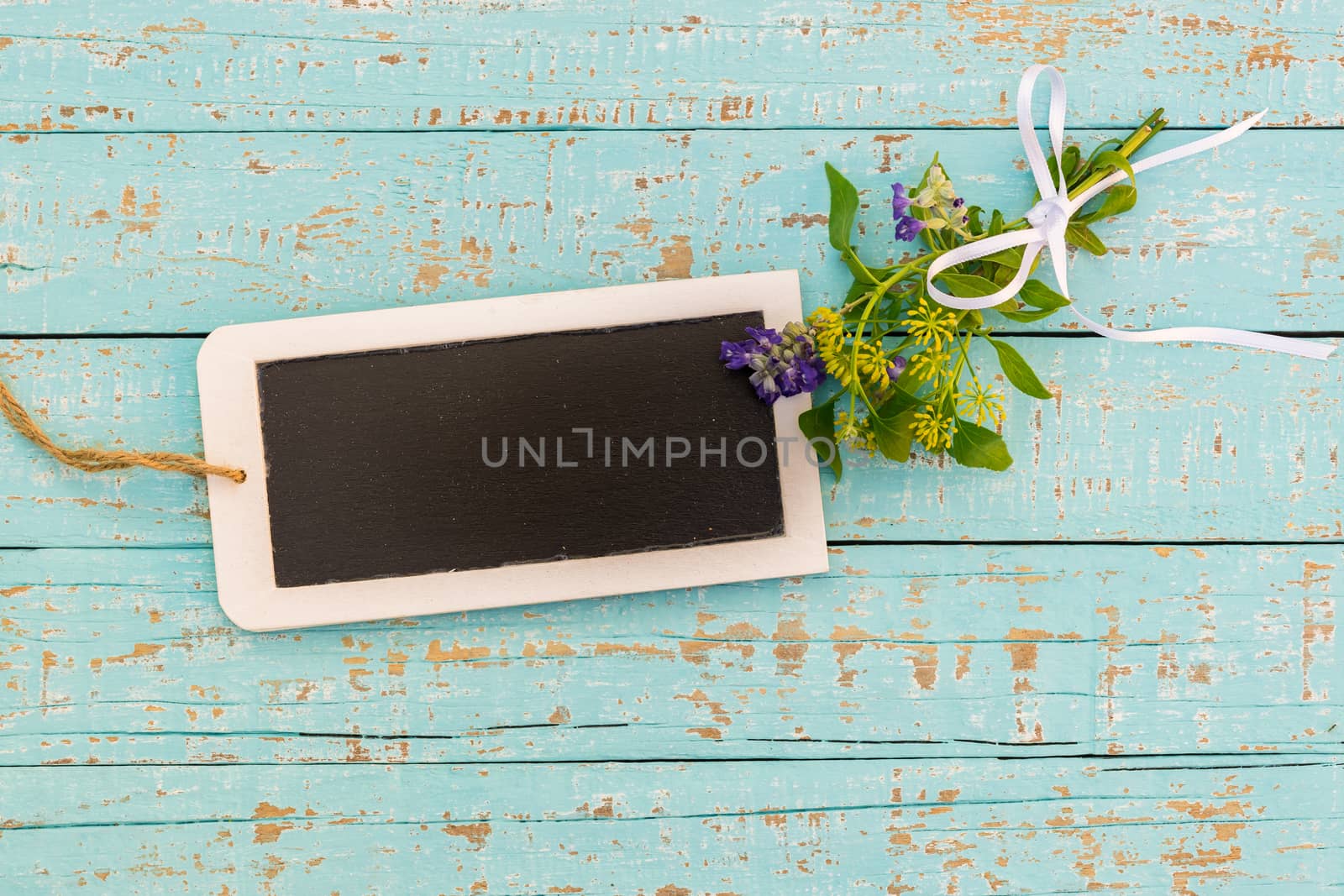 Bunch of flowers with small empty blackboard on blue wood background