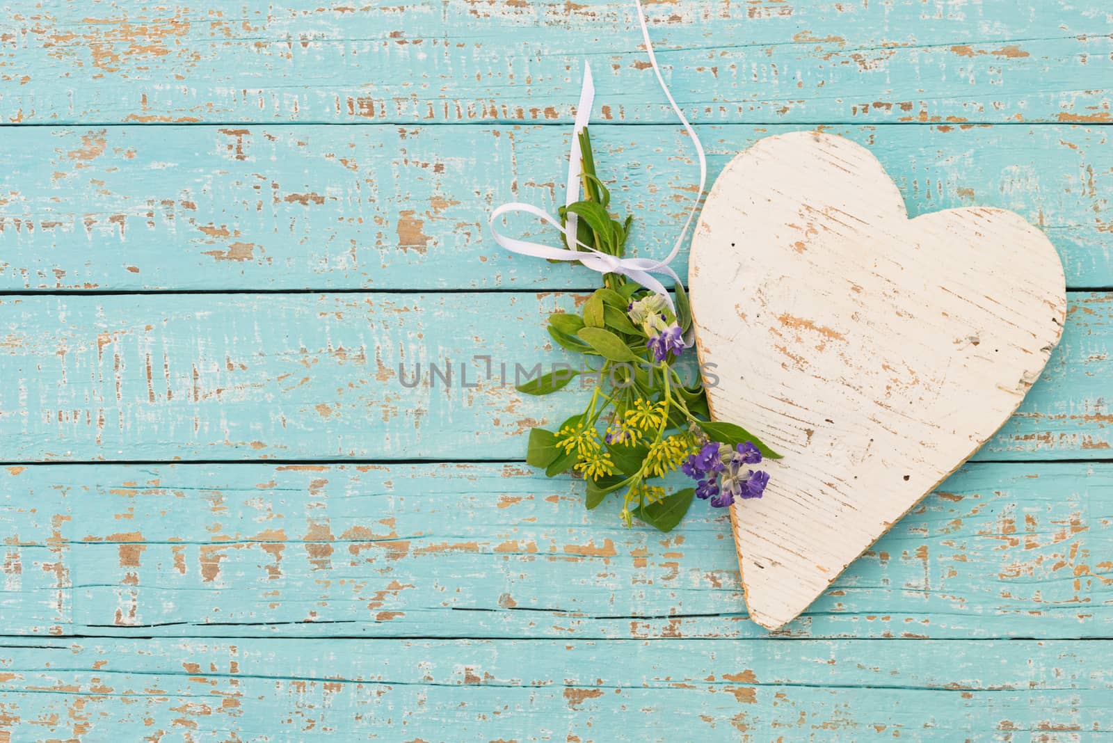 Turquoise background with white wooden heart and bunch of flowers with copy space