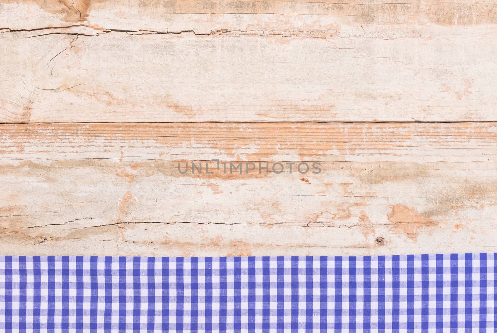 Rustic wooden table surface with blue checkered cloth, top view