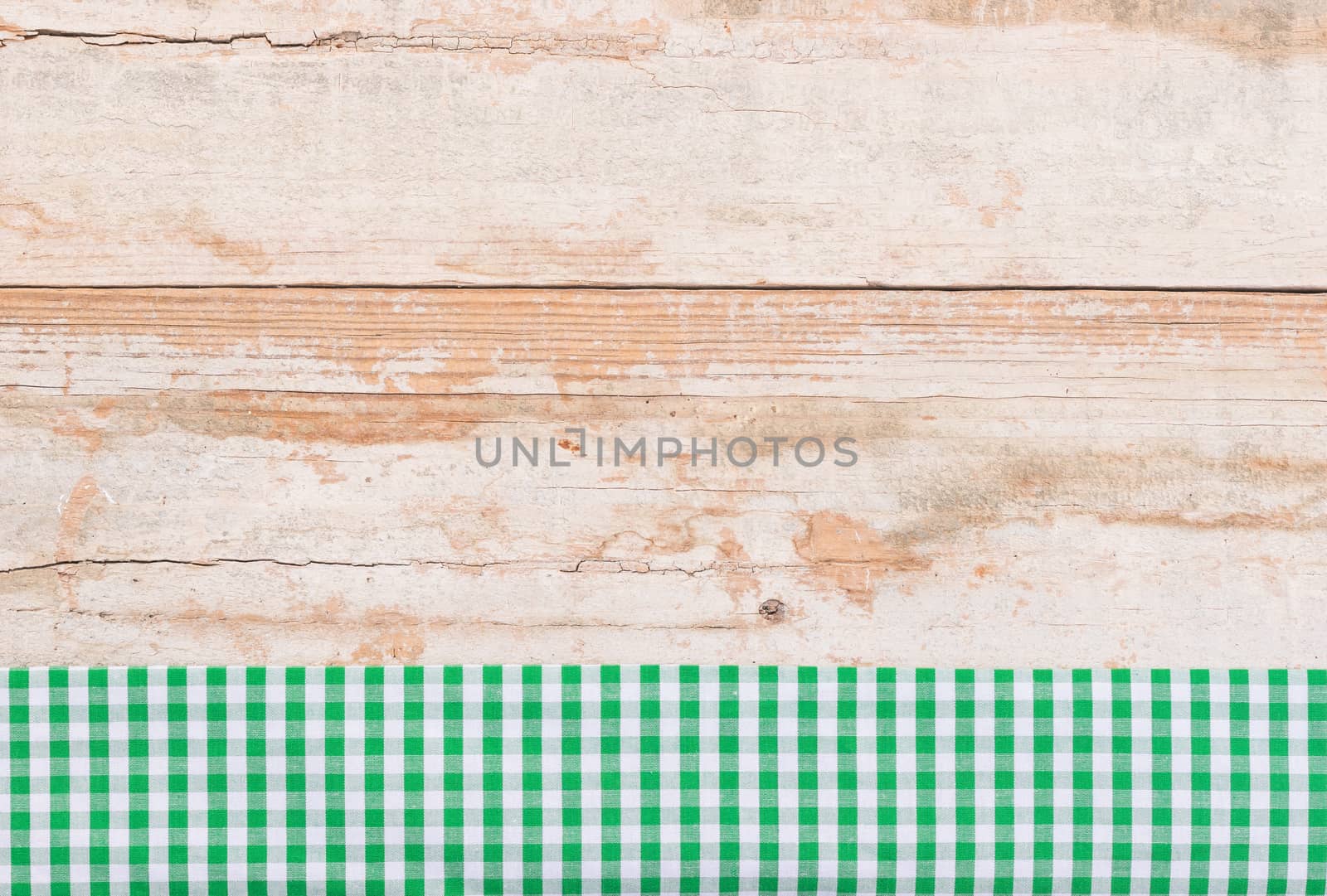 Rustic wooden table surface with green checkered cloth, top view