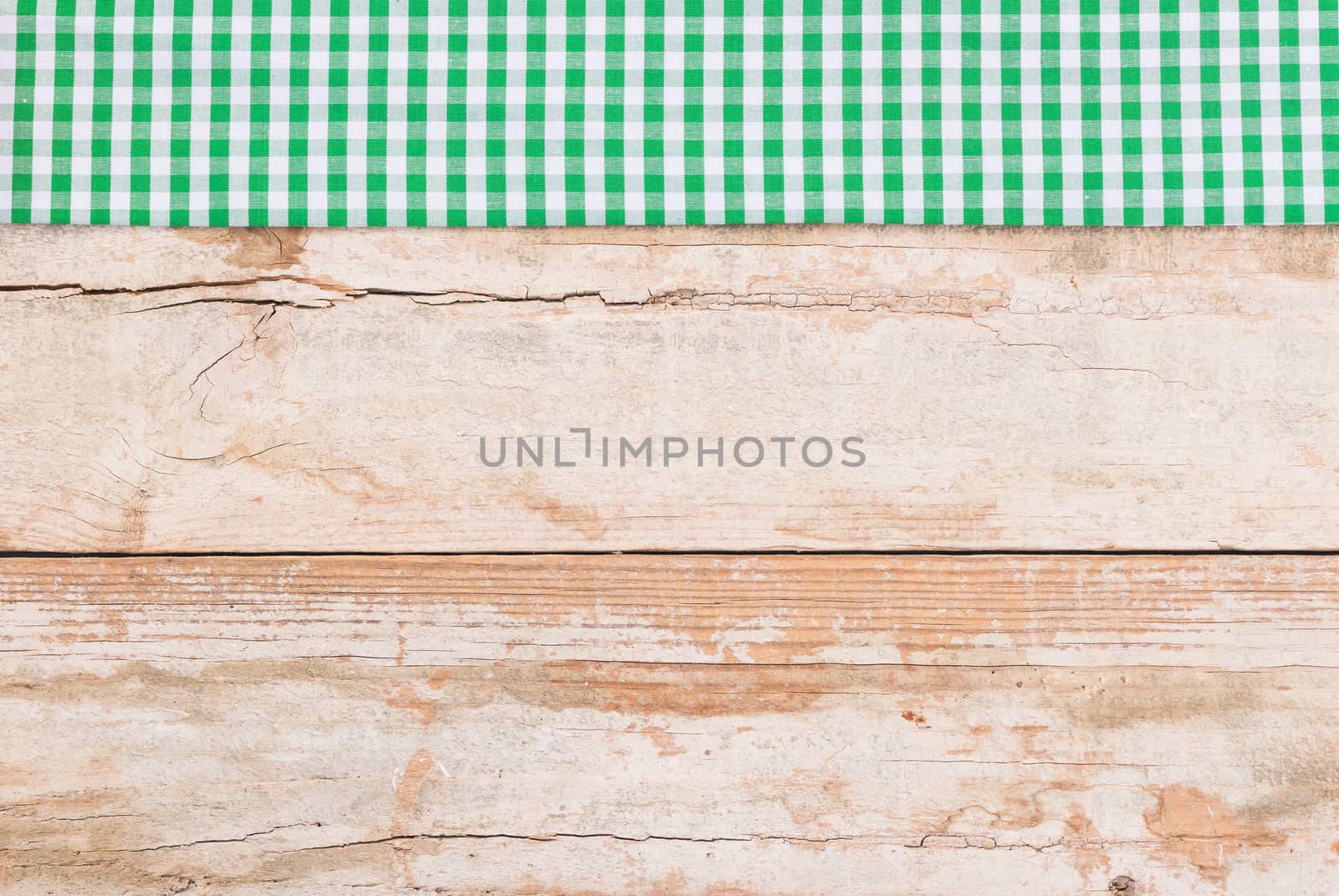 Rustic wooden table surface with green checkered cloth, top view