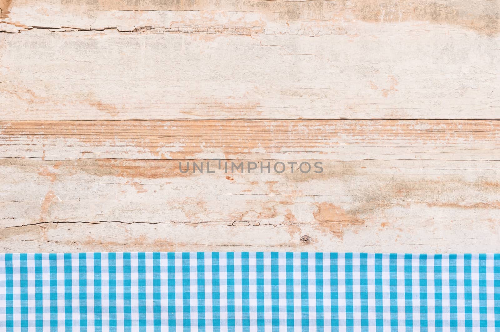 Rustic wooden table surface with blue checkered cloth, top view