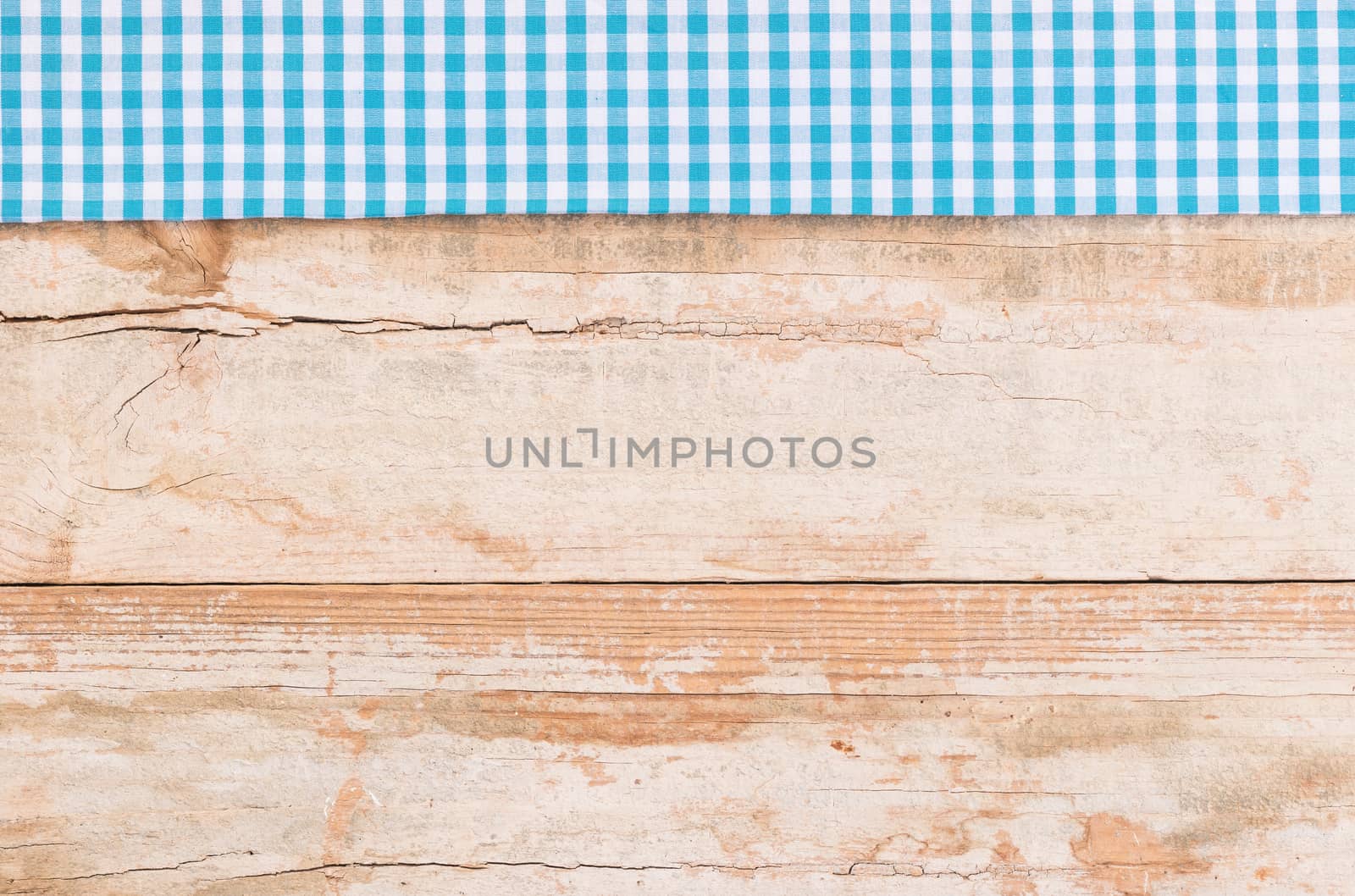 Rustic wooden table surface with blue checkered cloth, top view
