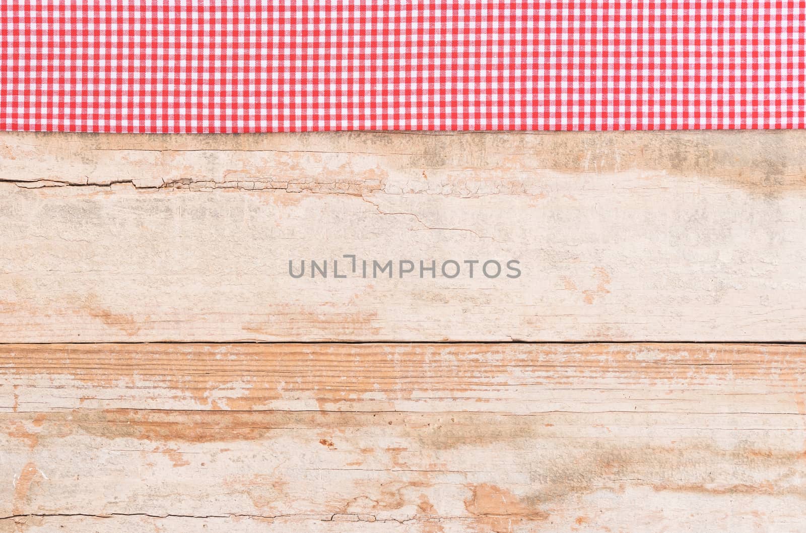 Rustic wooden table surface with red checkered cloth, top view