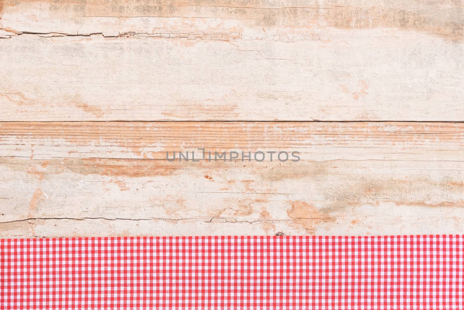 Rustic wooden table surface with red checkered cloth, top view