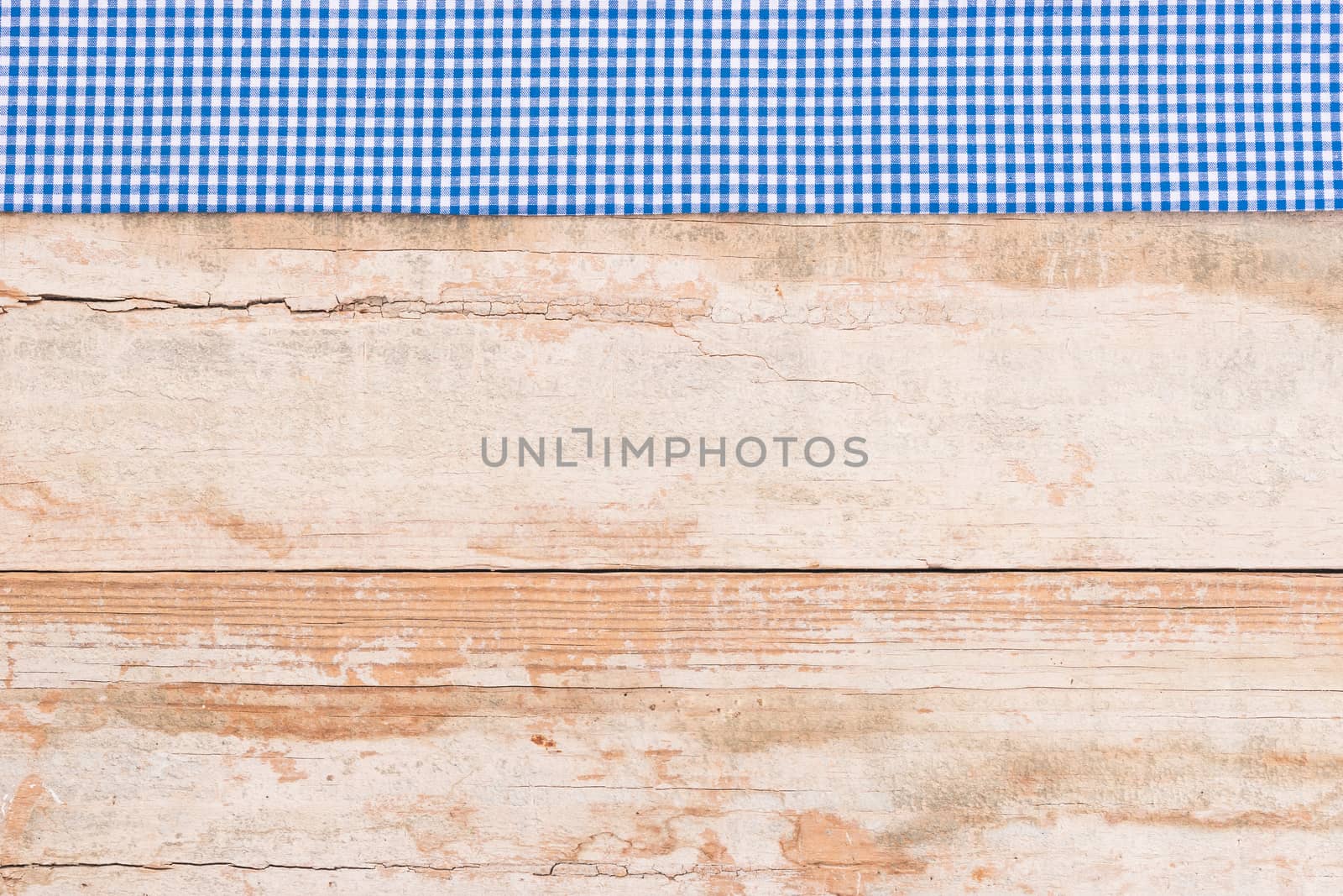 Rustic wooden table surface with blue checkered cloth, top view