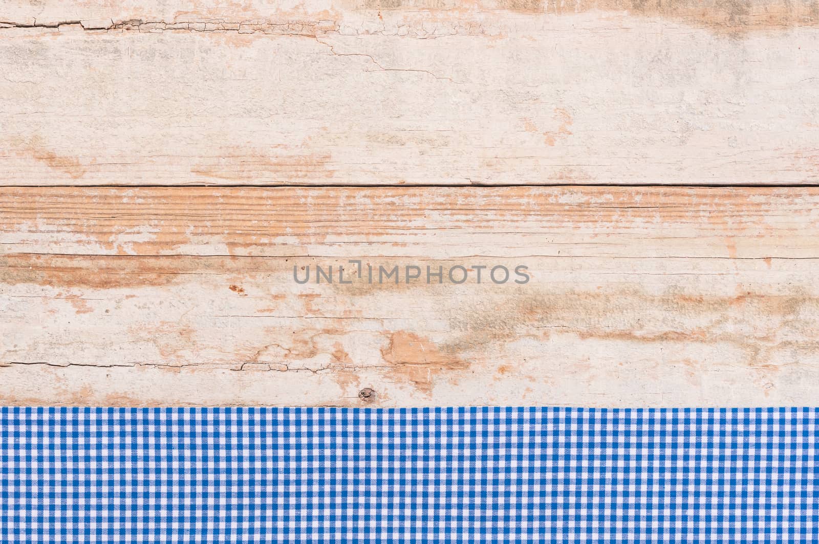 Rustic wooden table surface with blue checkered cloth, top view