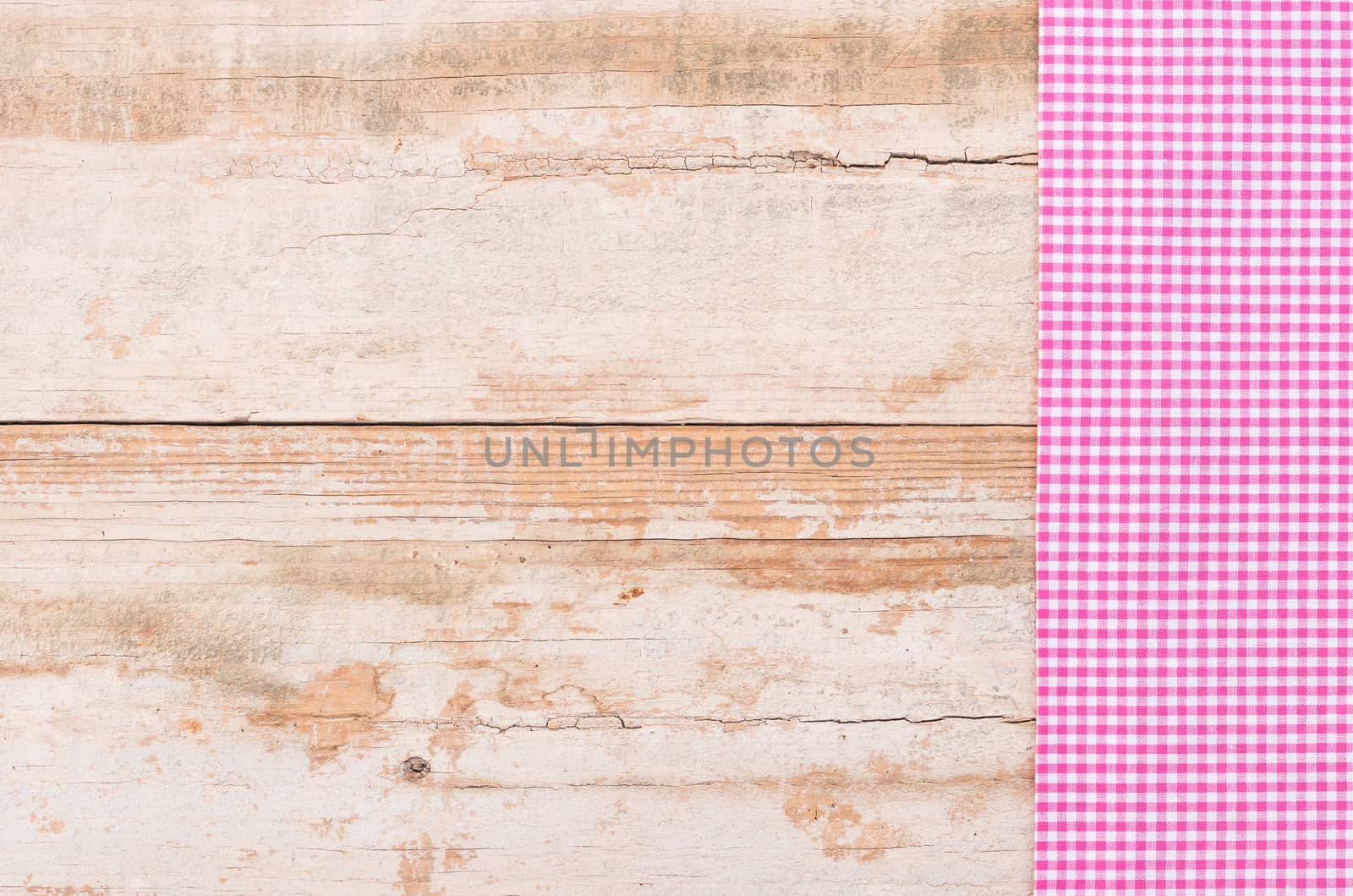 Pink checked tablecloth on rustic wooden table background, top view