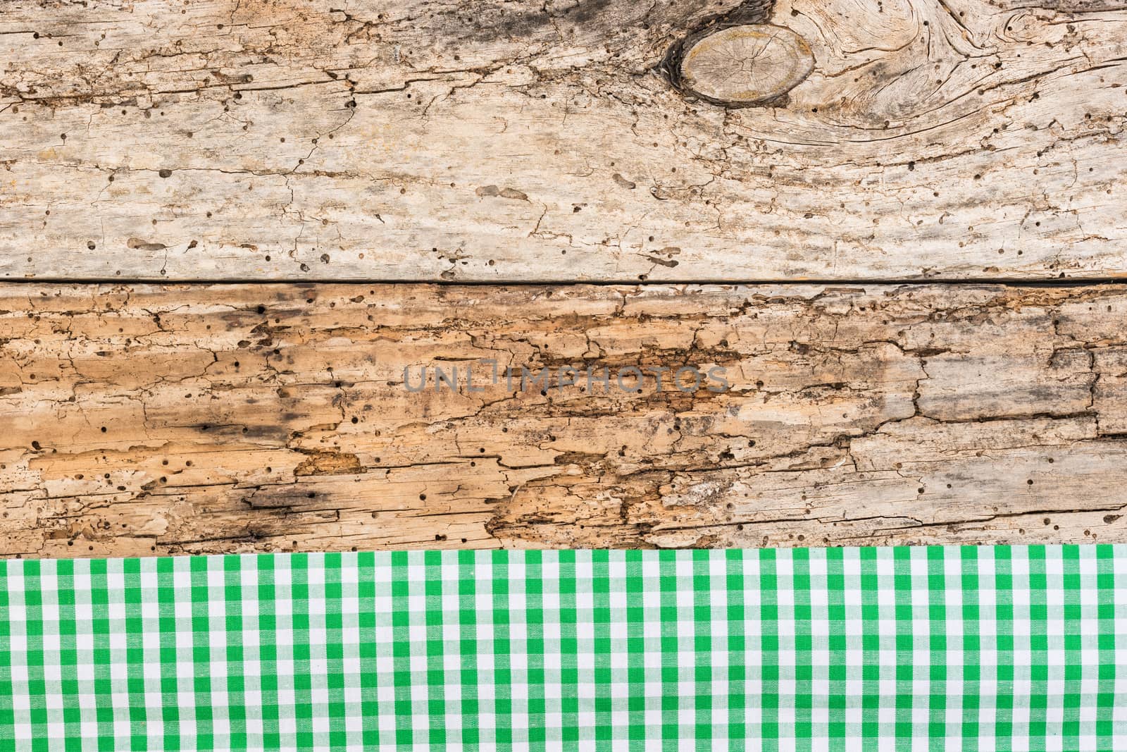 Rustic wooden table surface with green checkered cloth, top view